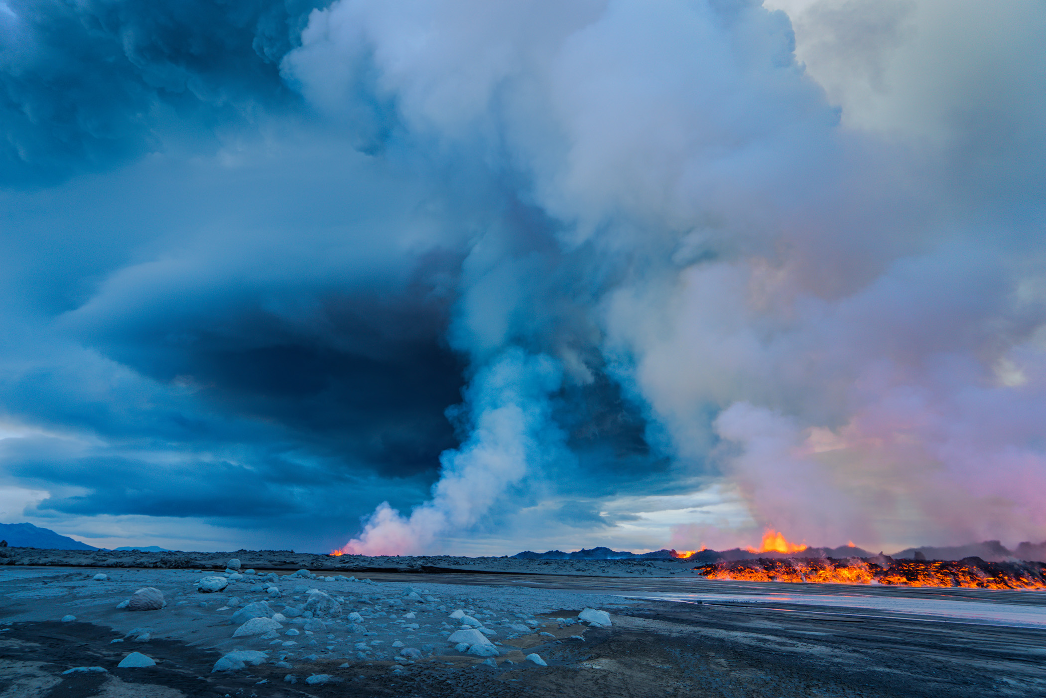 A late afternoon wide angle view over a part of the 2 km long fissure erupting and the cloud of fumes and steam rising into the air.