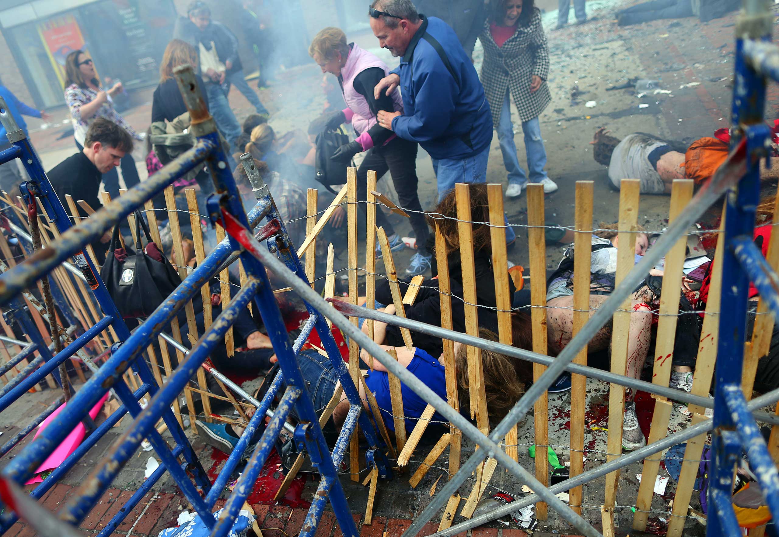 April 15, 2013. Victims lie on the sidewalk near a barrier at the scene of the first explosion.