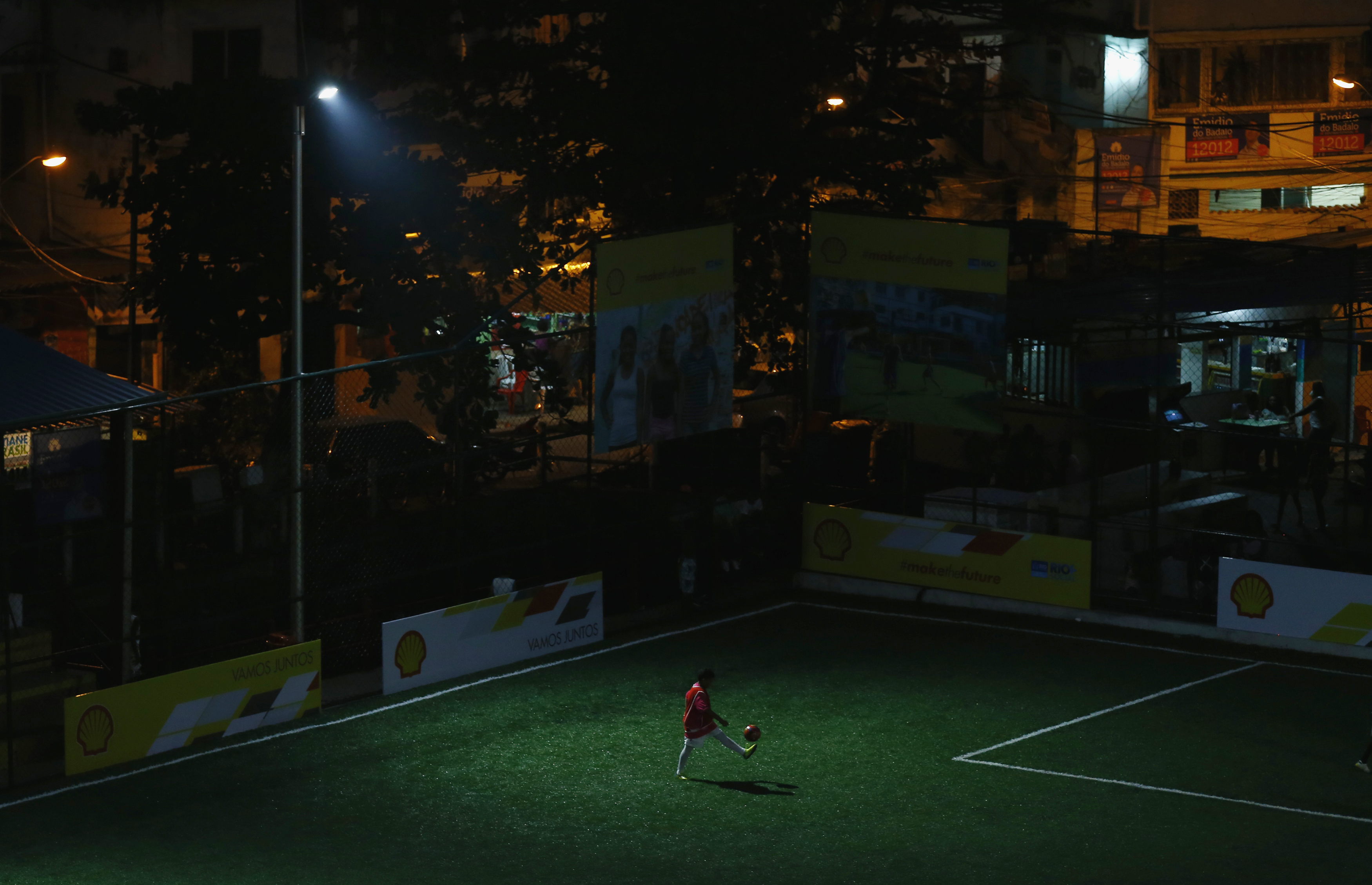 Kid plays with soccer ball at a refurbished soccer field at the Mineira slum in Rio de Janeiro
