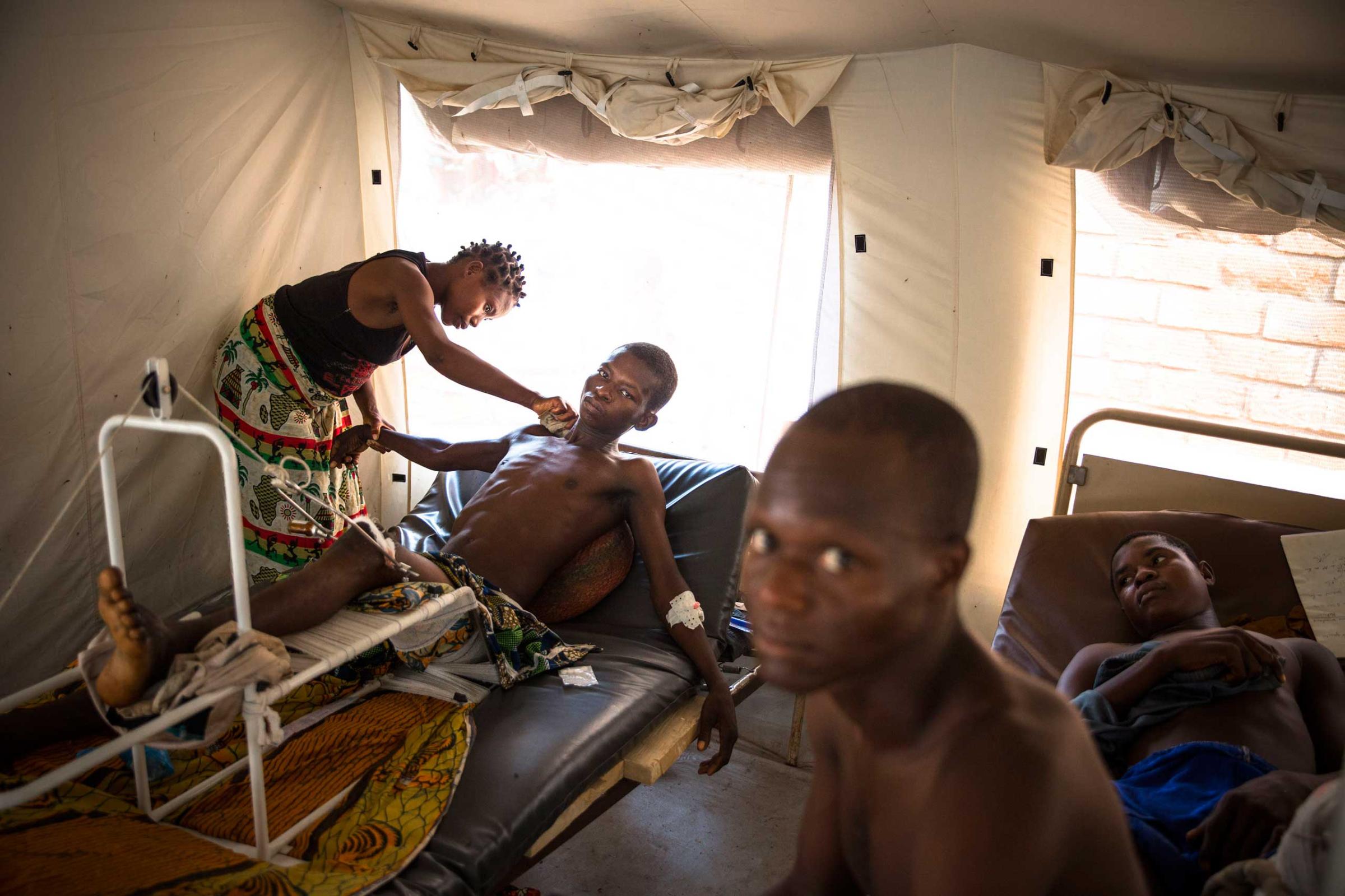 Jan. 31, 2014: A man wounded during previous days of fighting between Christians and Muslims is washed by his wife in a tent in Bangui's community hospital.
