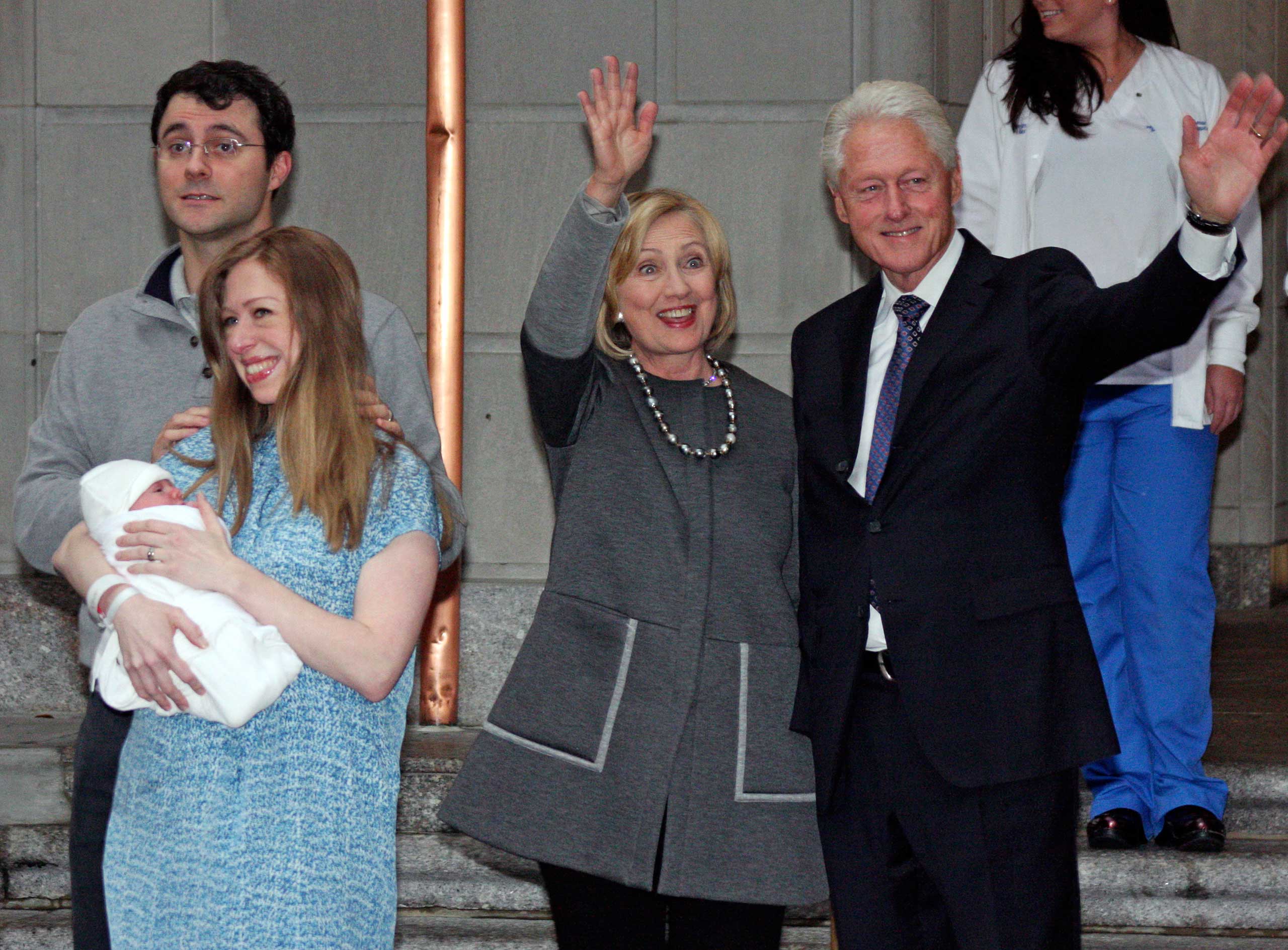 Former President Bill Clinton, right, and former Secretary of State Hillary Rodham Clinton, second from right, wave to the media as Marc Mezvinsky and Chelsea Clinton pose for photographers with their newborn baby, Charlotte, after the family leaves Manhattan's Lenox Hill hospital in New York City on Sept. 29, 2014.
