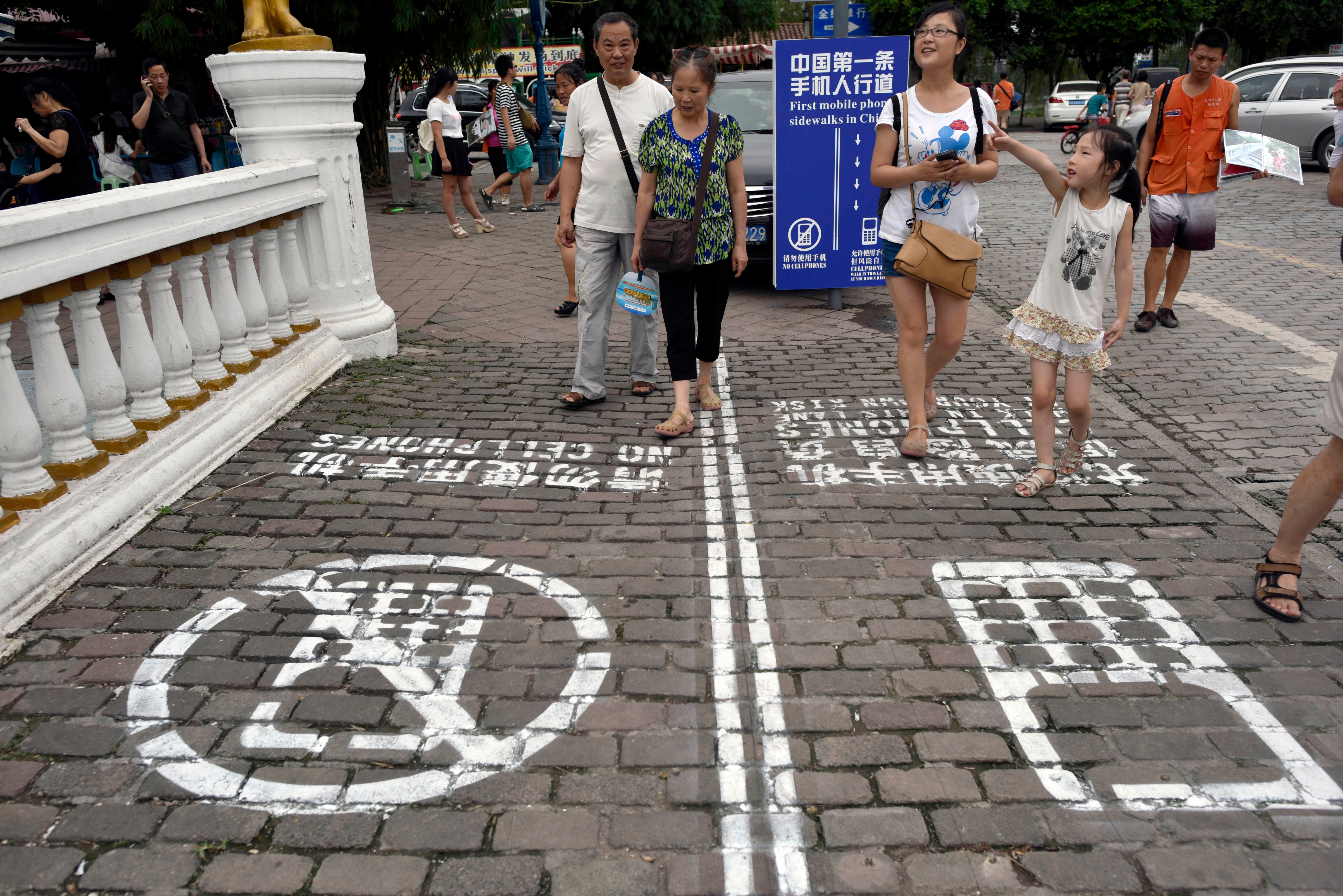 In this photo taken Saturday, Sept. 13, 2014, residents walk on a lane painted with instructions to separate those using their phones as they walk from others in southwest China's Chongqing Municipality. (AP)