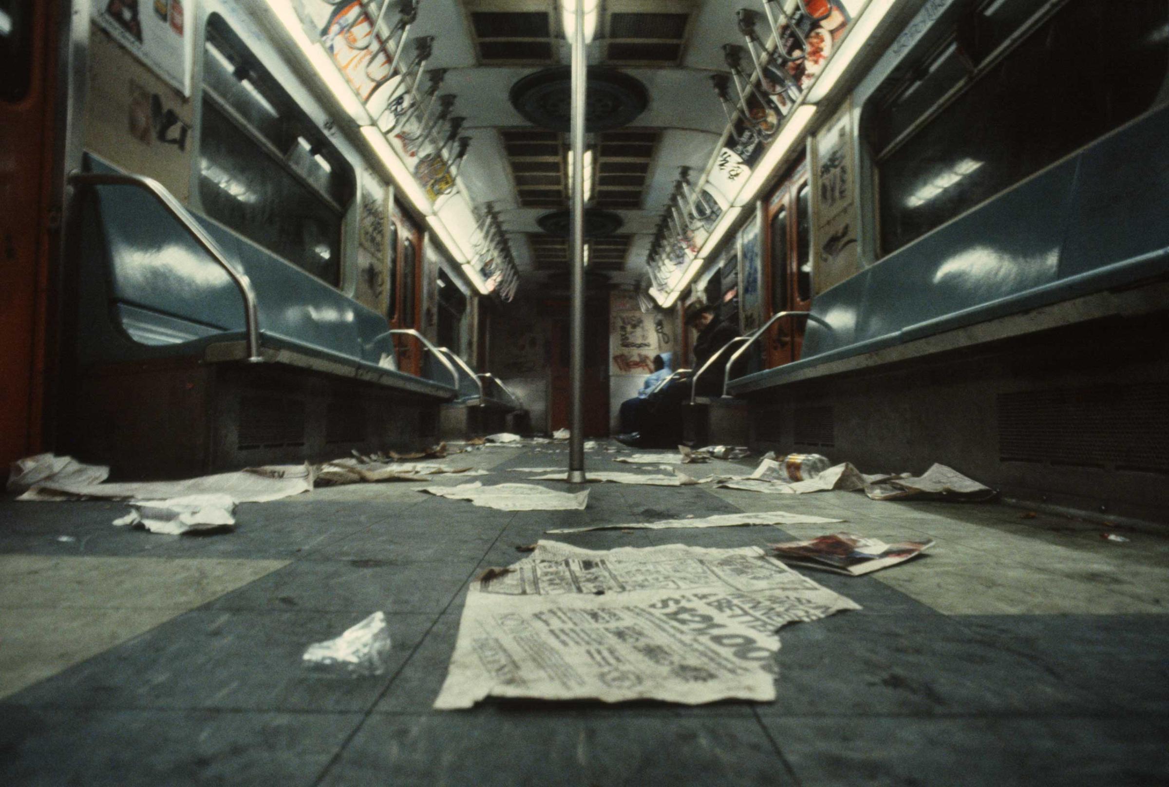 Discarded newspapers and trash on the floor of a subway car, 1981.