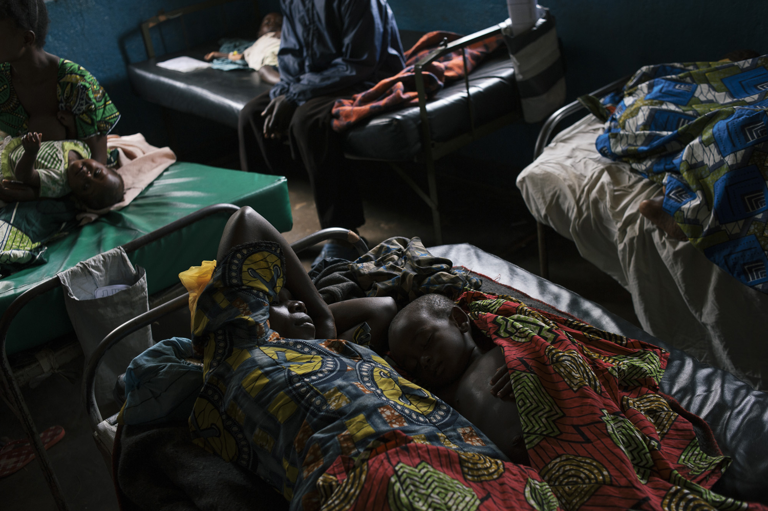 A mother lays next to her child who is suffering from malaria in the health centre in Nyabiondo. Staff at the health centre say they are dealing with an epidemic of malaria. Few people have mosquito nets, July 21, 2014.