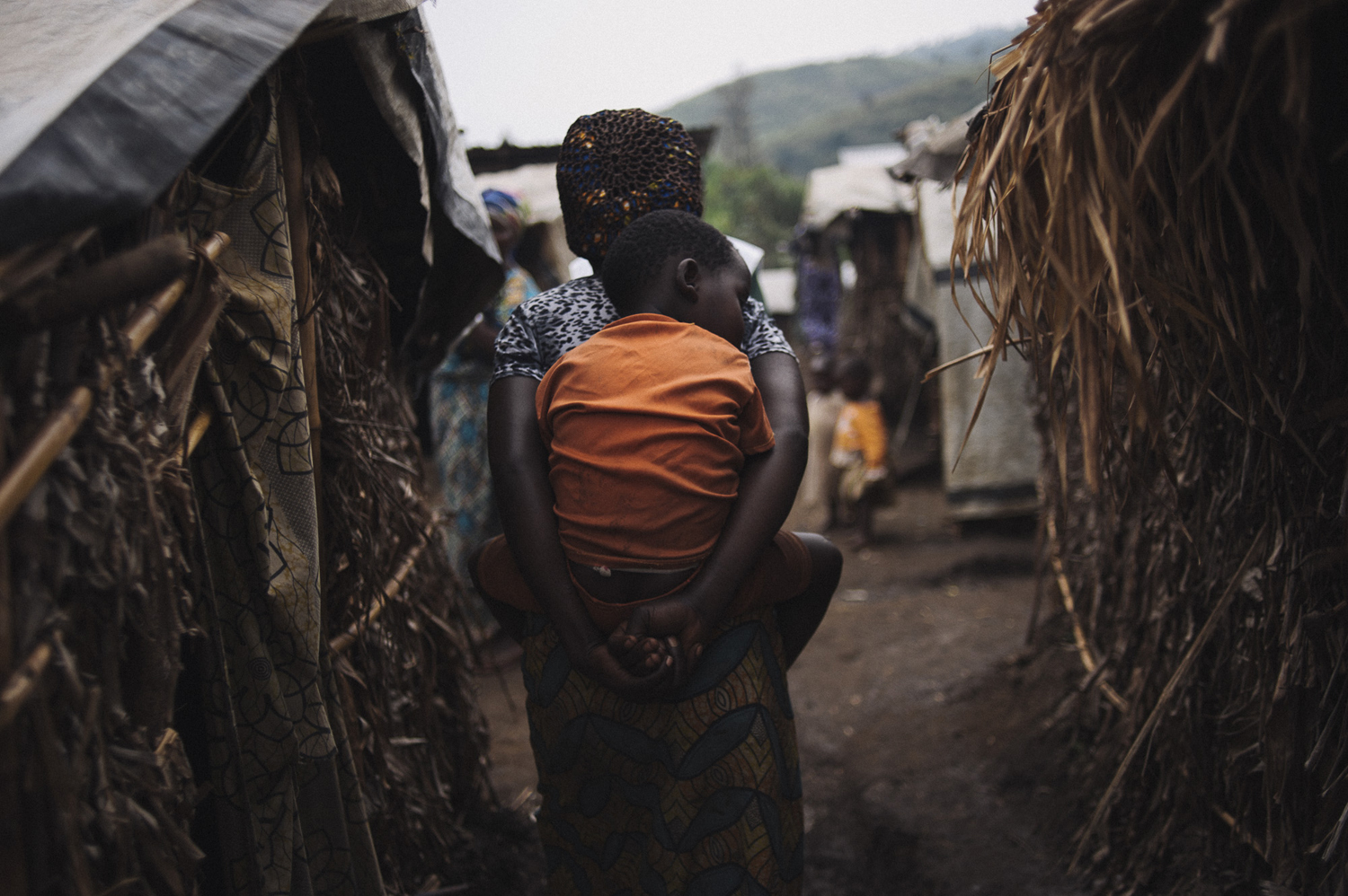 Fifi Bahati (33), a displaced Congolese lady, carries her child through the Birere I displacement camp in the town of Nyabiondo. "It was war that made me leave Kinyumba to come here" says Fifi, a mother of four. "We want to go home, but until peace is reestablished, we can't go back.", July 21, 2014.