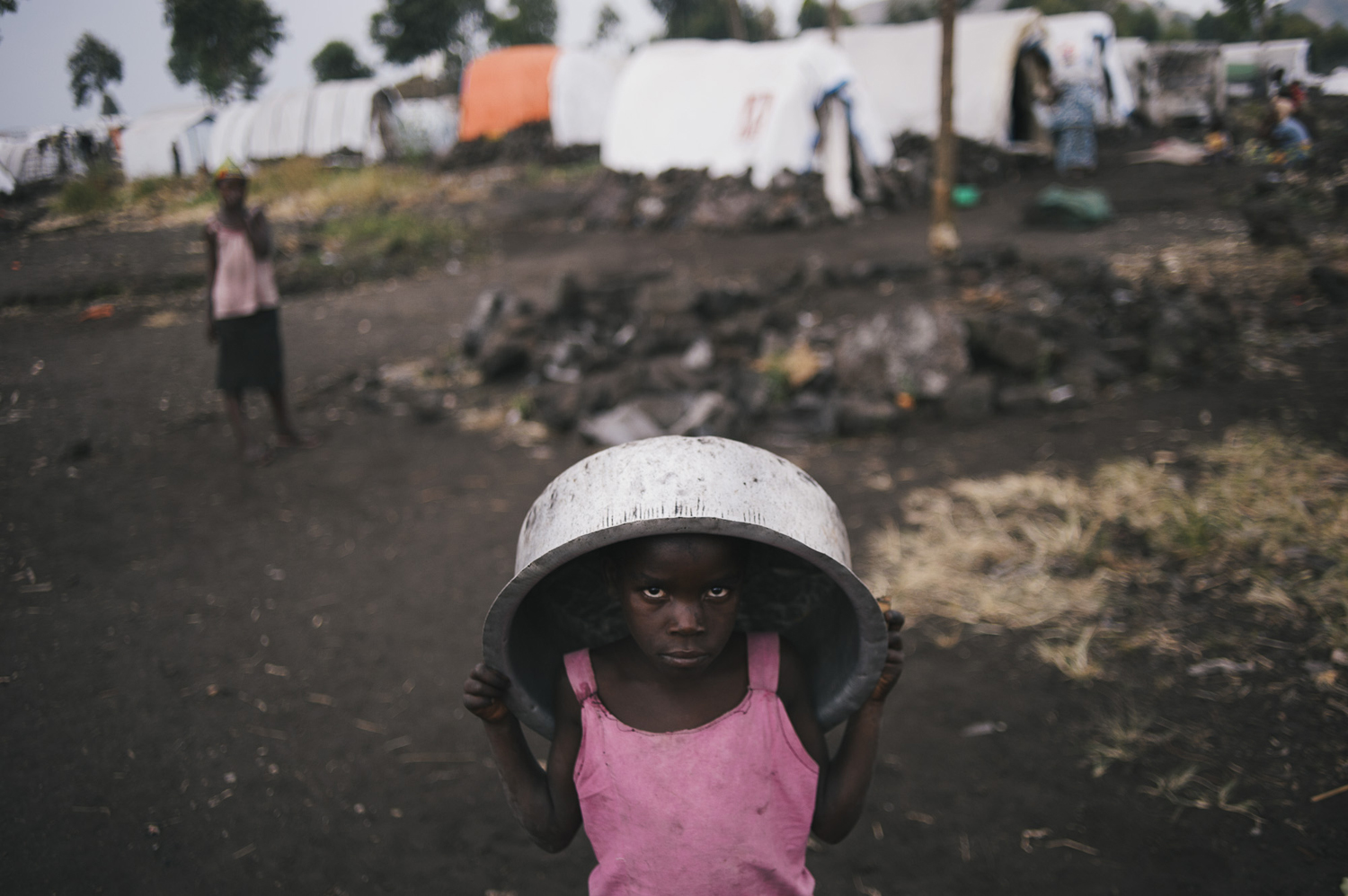 A displaced Congolese child stands with a basin on her head in the Bulengo site for internally displaced persons, July 14, 2014.