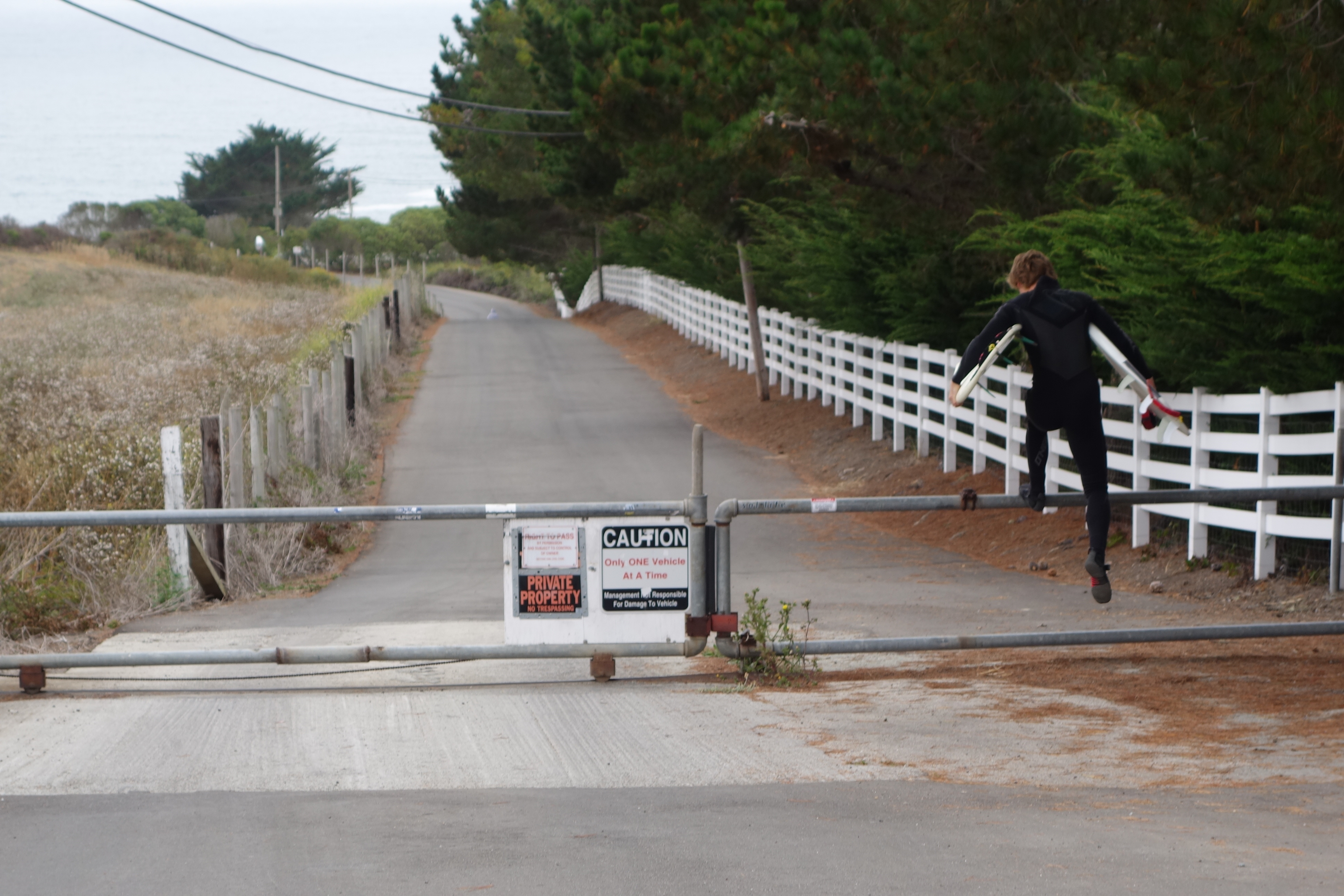 A surfer hops the gate at the top of Martins Beach Road, crossing property owned by venture capitalist Vinod Khosla in order to get to Martins Beach on August 7, 2014. (Katy Steinmetz for TIME)