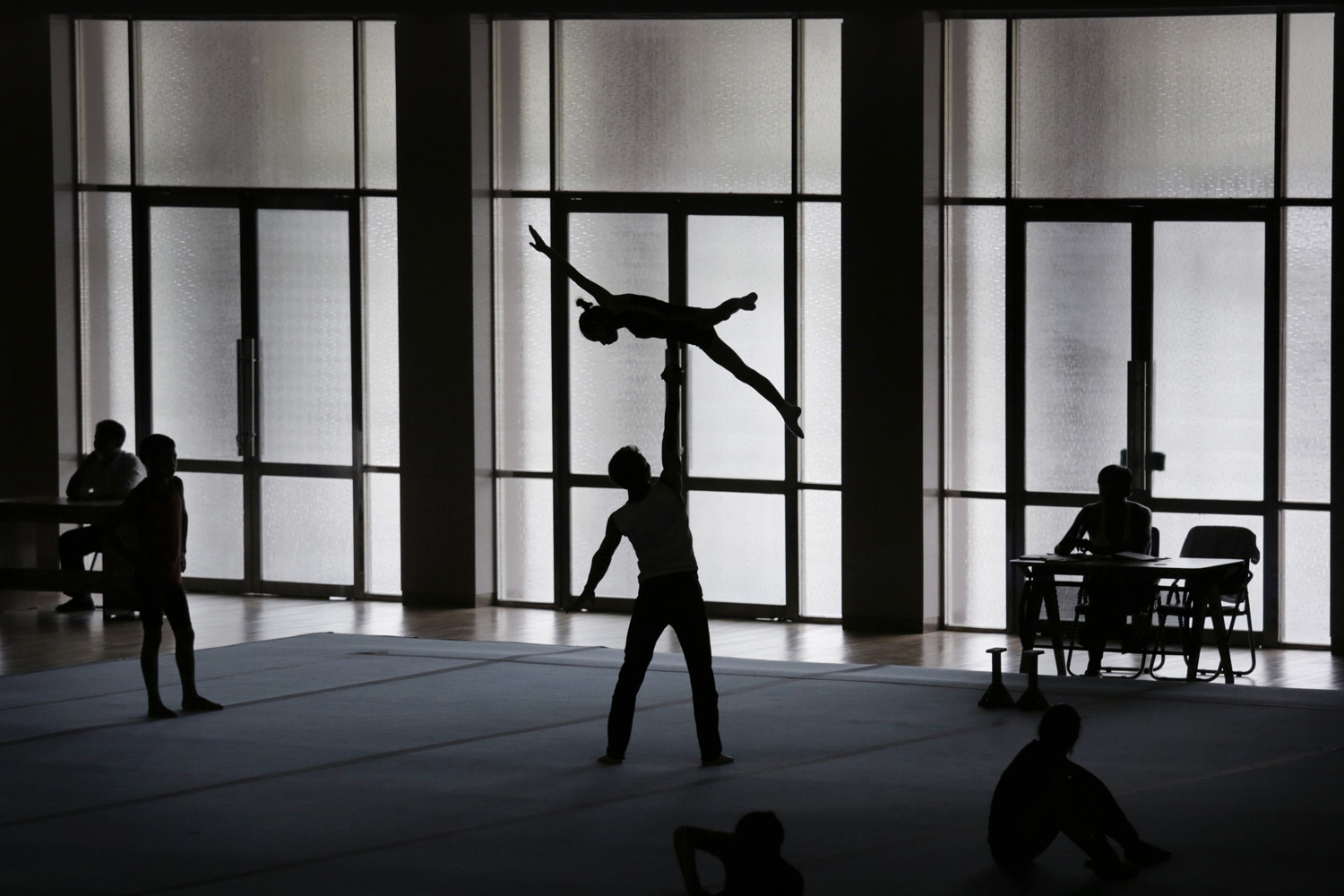 Gymnasts are silhouetted as they practice their routine in Pyongyang, Sept. 2, 2014.