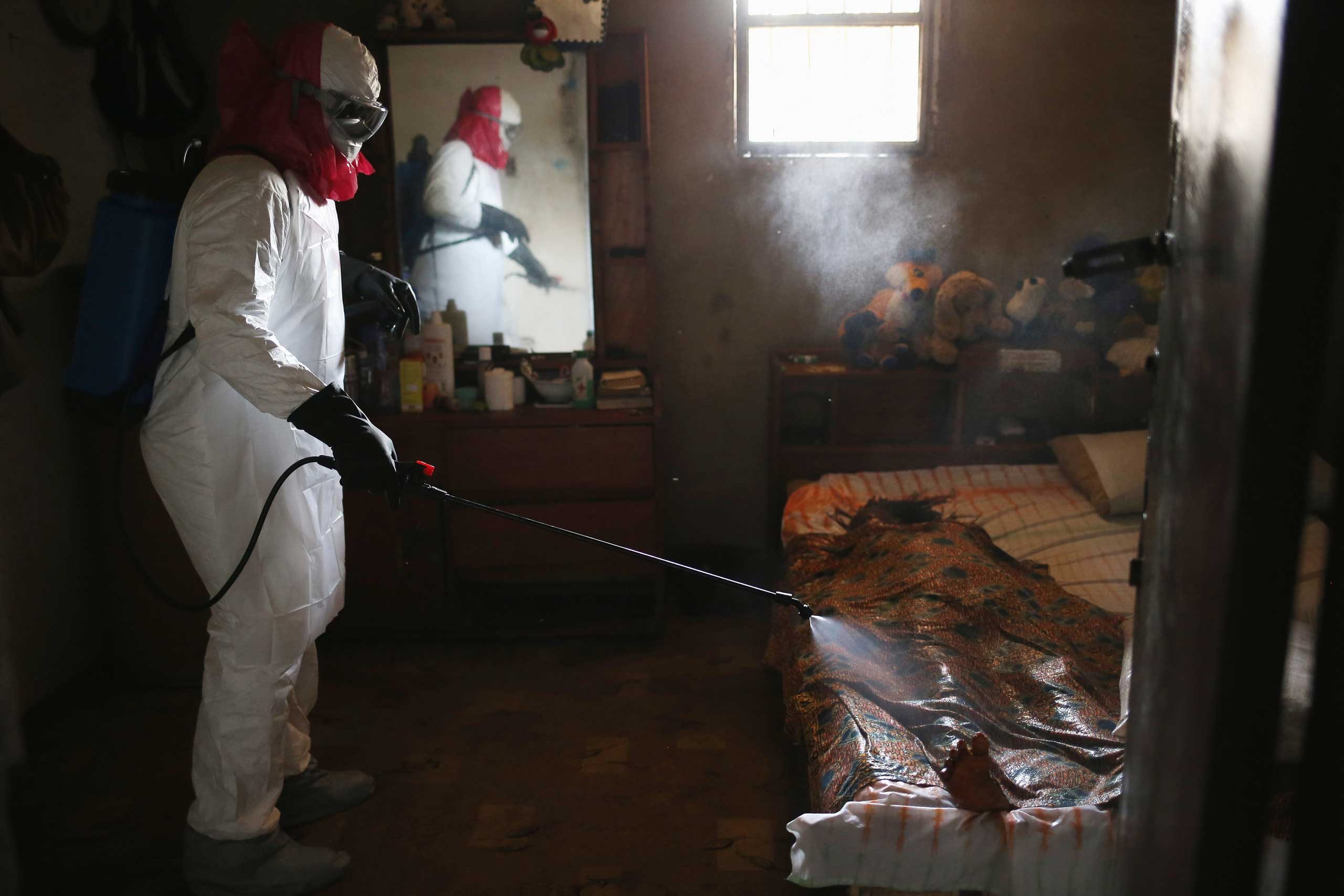 A burial team from the Liberian health department sprays disinfectant over the body of a woman suspected of dying of the Ebola virus on Aug. 14, 2014 in Monrovia. (John Moore—Getty Images)