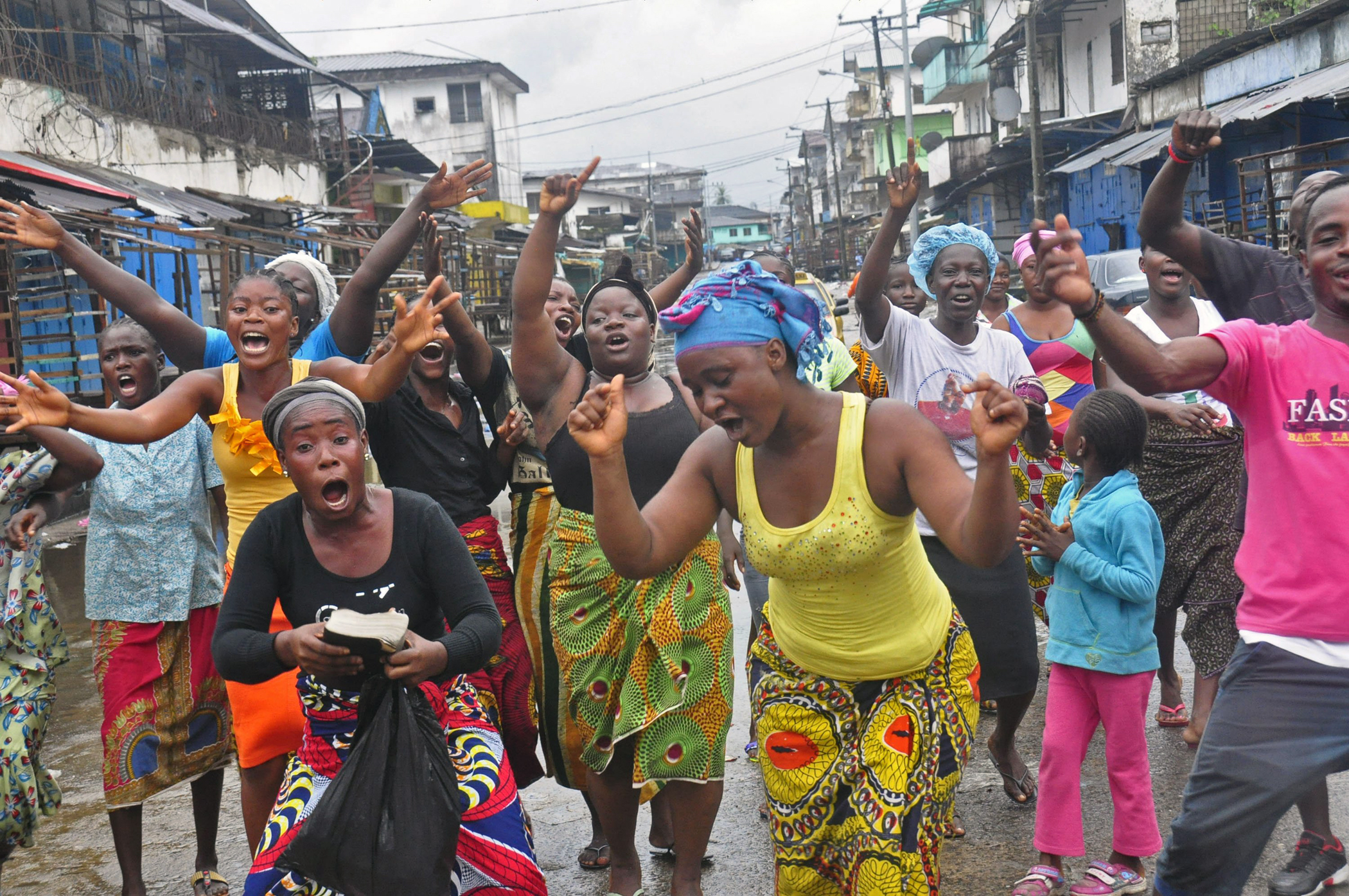 People celebrate in a street outside of West Point slum in Monrovia, Liberia, Aug. 30, 2014. Crowds cheer and celebrate in the streets after Liberian authorities reopened a slum where tens of thousands of people were barricaded amid the countryís Ebola outbreak.