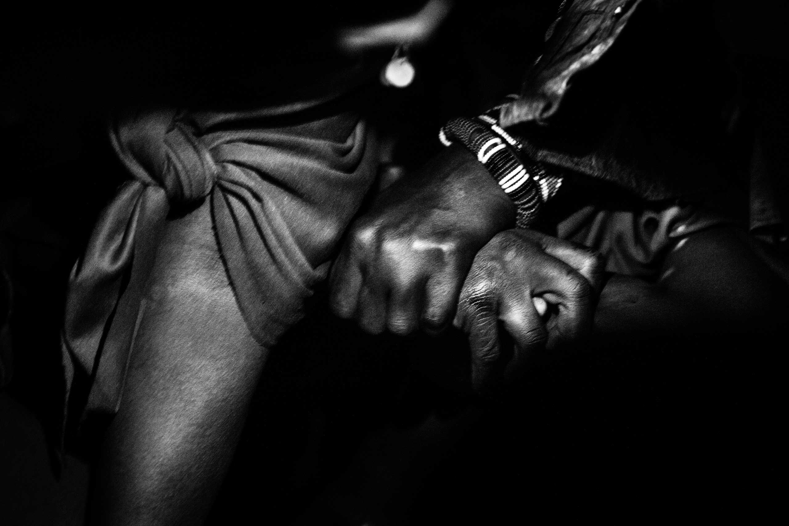 A woman holds Isina's wrist as the girl, in severe pain, struggles during her circumcision.