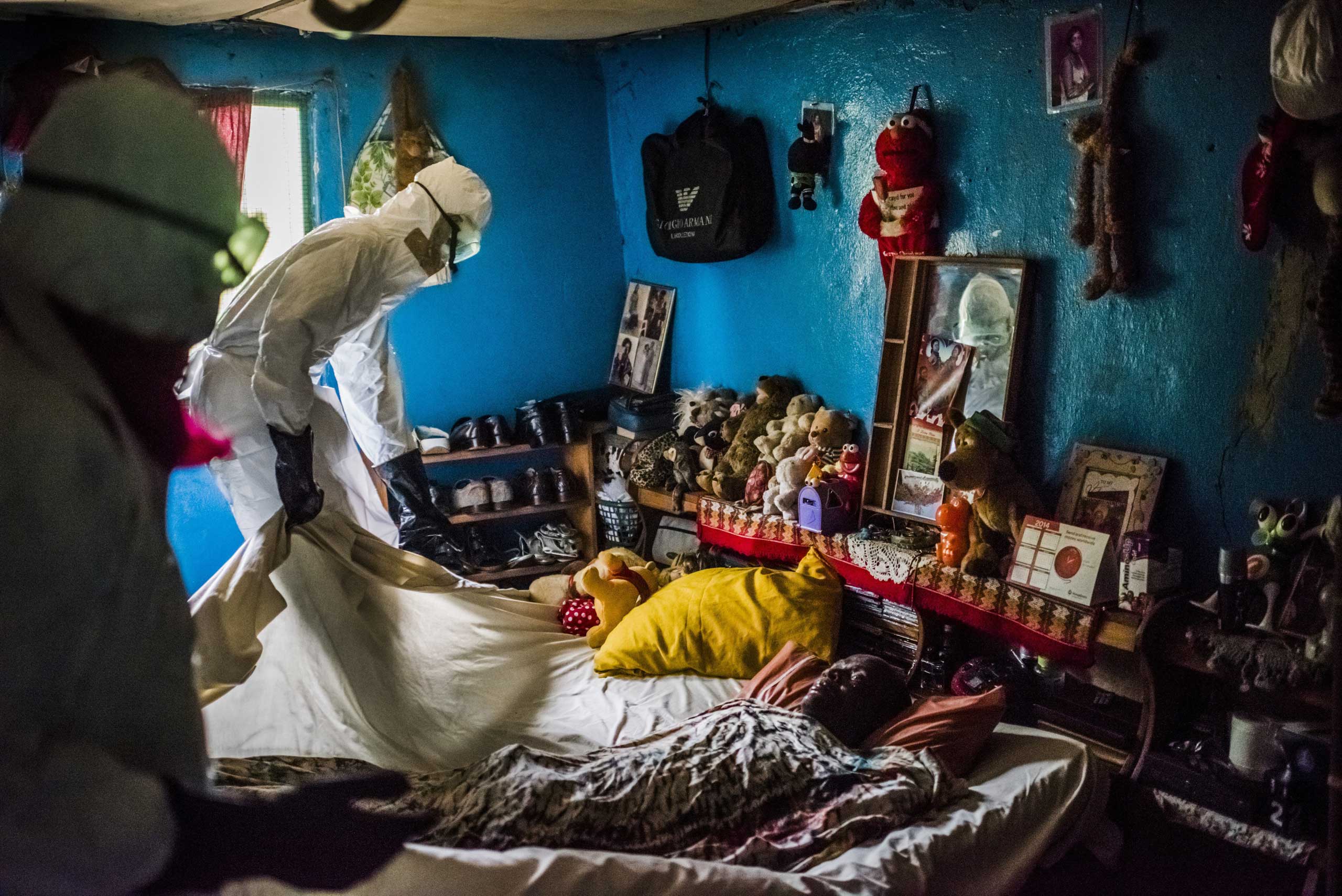 Sept. 17, 2014. A Liberian Red Cross burial team remove the body of a suspected Ebola victim from a home in Monrovia, Liberia.