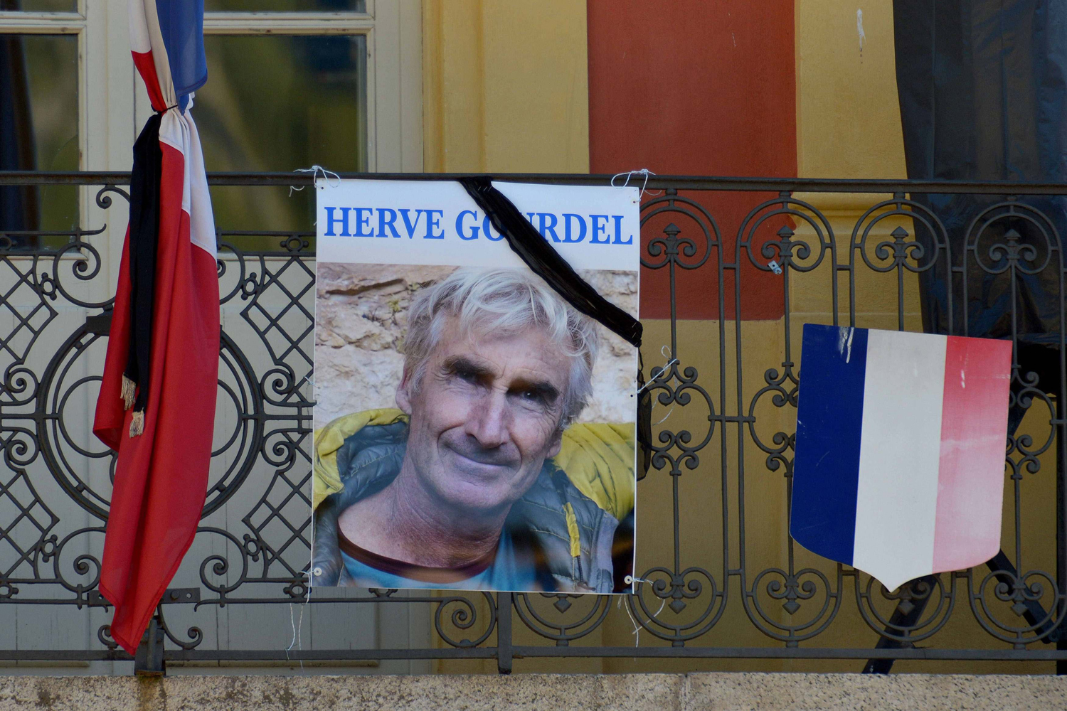 A portrait of mountain guide Frenchman Herve Gourdel hangs near a French flag outside the town hall in Saint-Martin-Vesubie, Sept. 25, 2014.