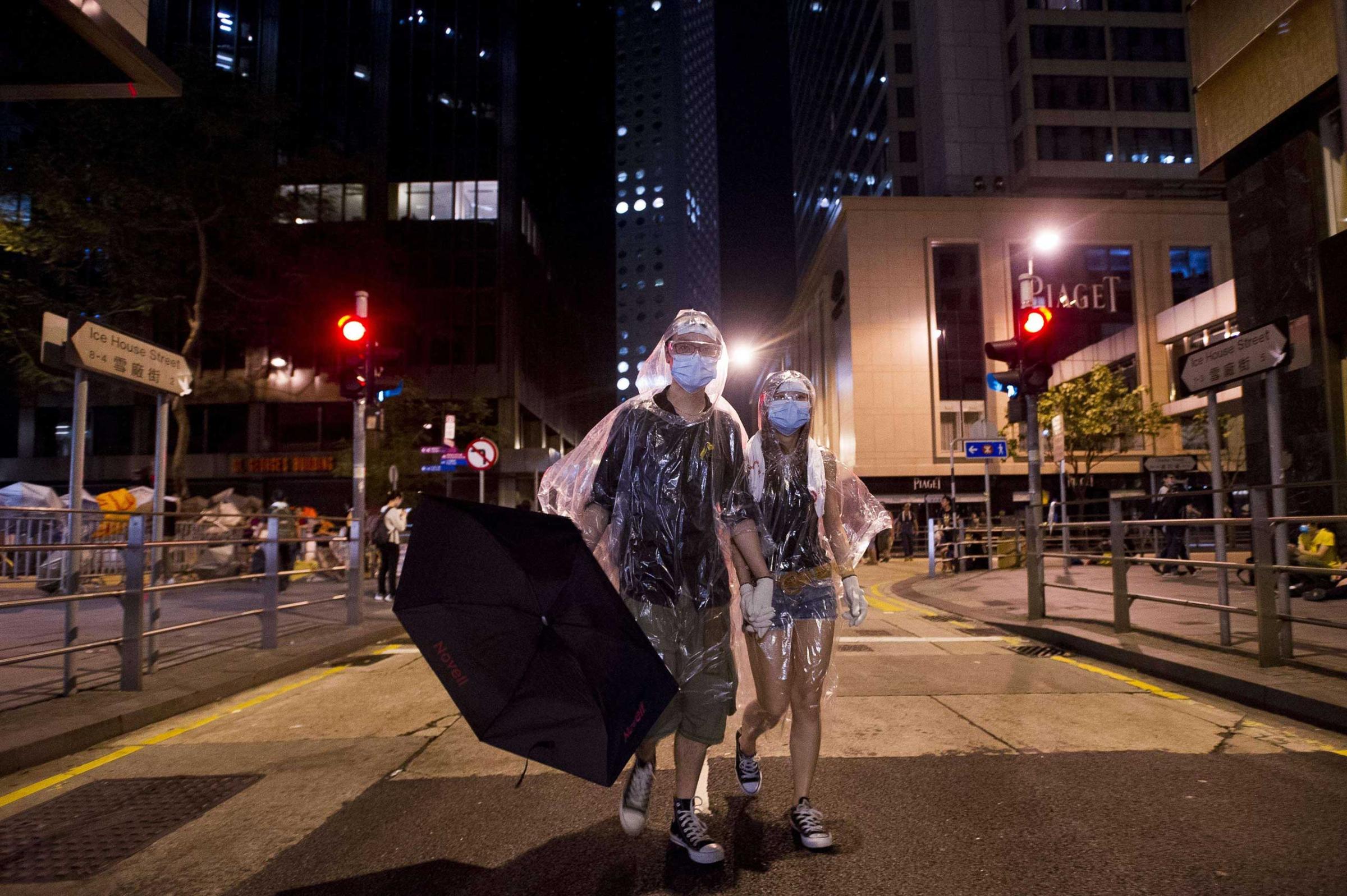 A couple wearing protective masks and ponchos walk through Admiralty district as part of pro-democracy protests in Hong Kong on Sept. 30, 2014.