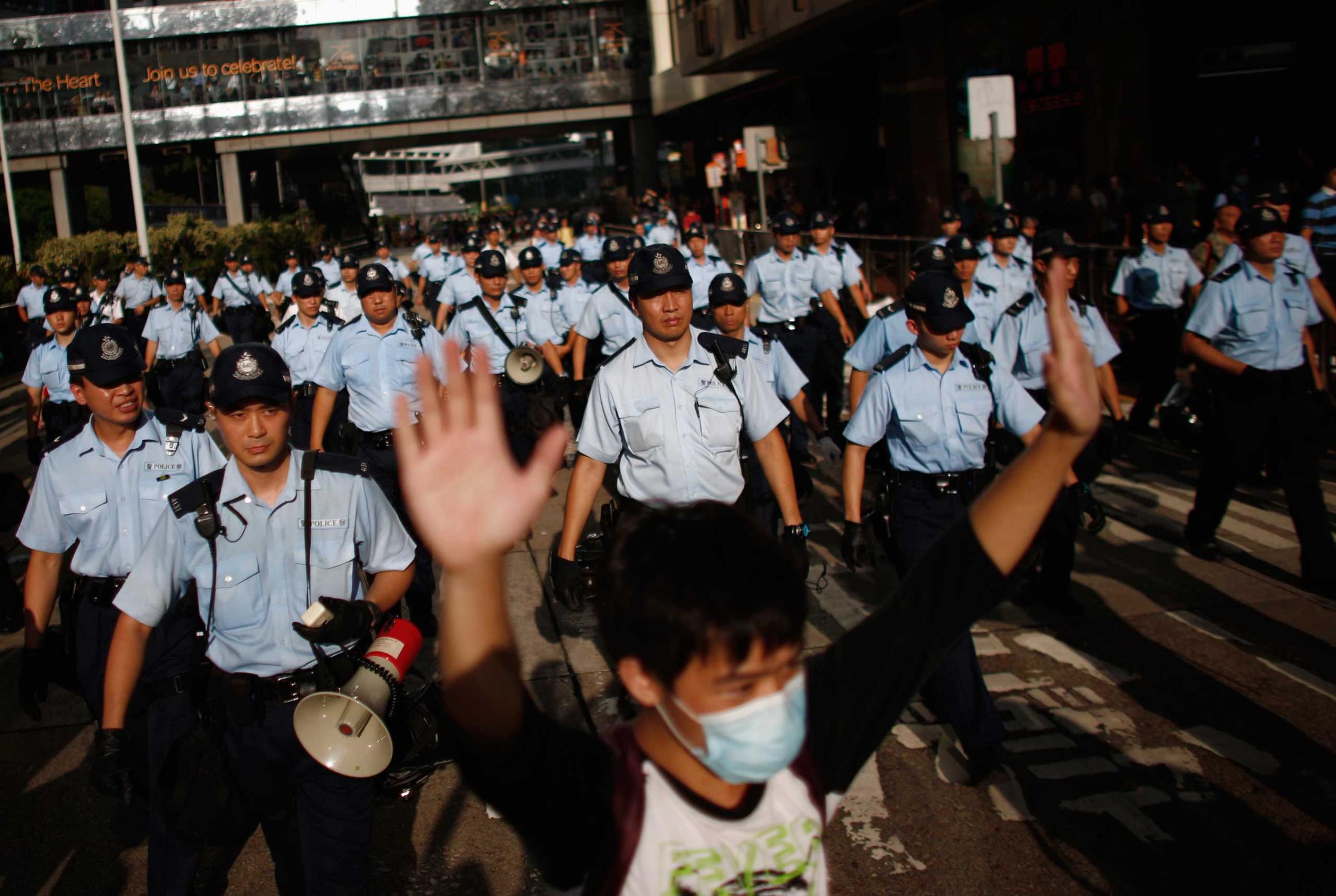 A protester raises his arms as police officers try to disperse the crowd near the government headquarters in Hong Kong, Sept. 29, 2014.