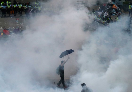 A protester walks in tear gas fired by riot policemen after thousands of protesters blocking the main street to the financial Central district outside the government headquarters in Hong Kong, Sept. 28, 2014.