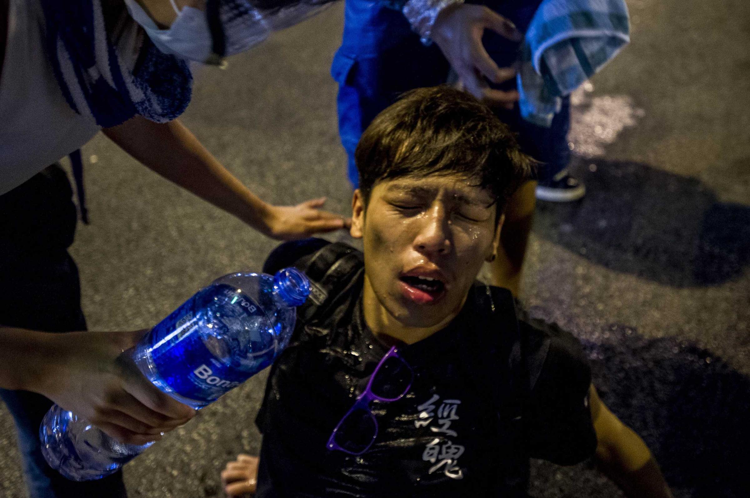 A pro-democracy demonstrator pours water over a man's face after police fired tear gas at protesters during a rally near the Hong Kong government headquarters on Sept. 28, 2014.