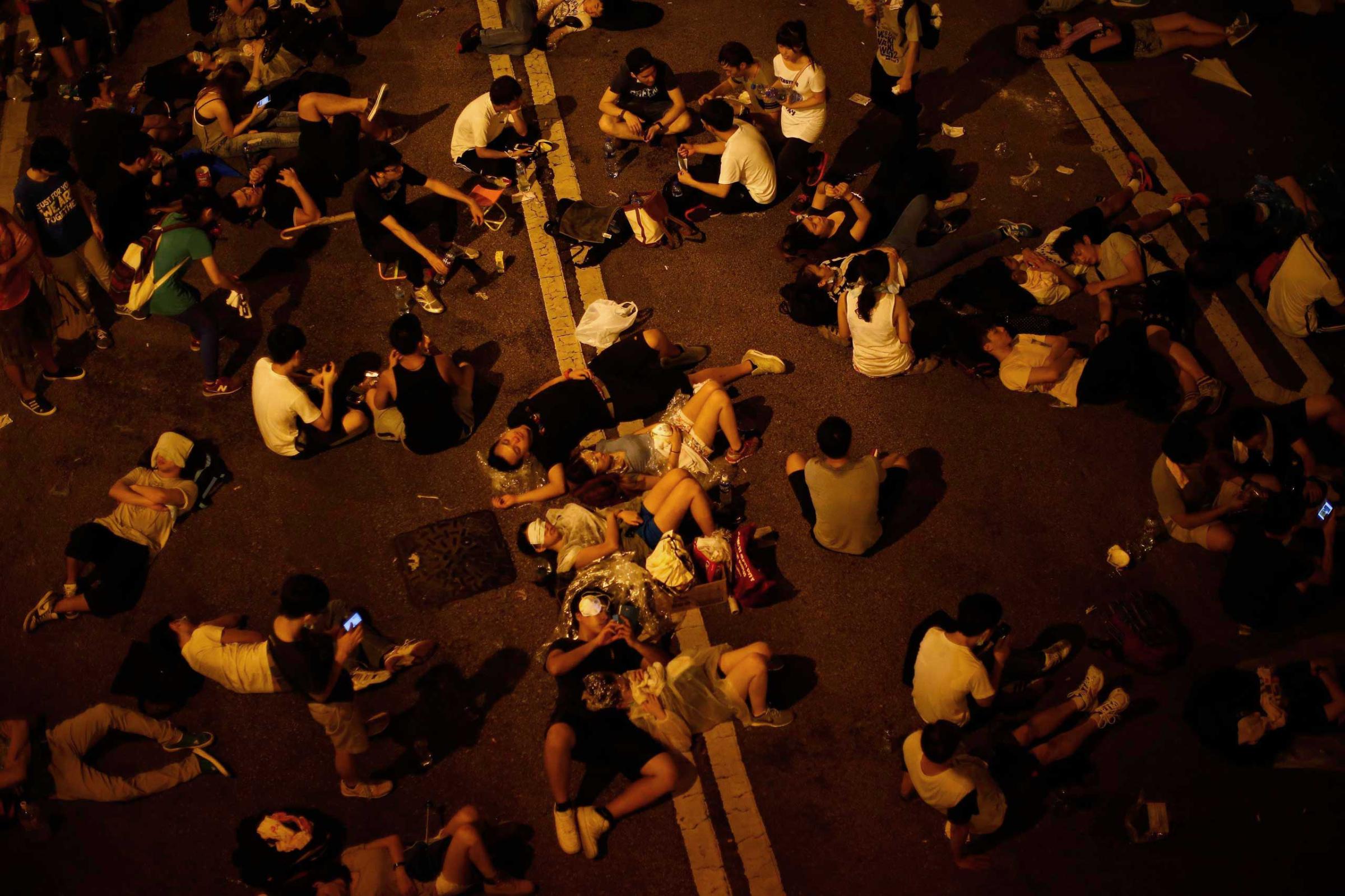 Some of the protesters sleep as they block the main street to the financial Central district outside the government headquarters, with other demonstrators in Hong Kong, Sept, 29, 2014.