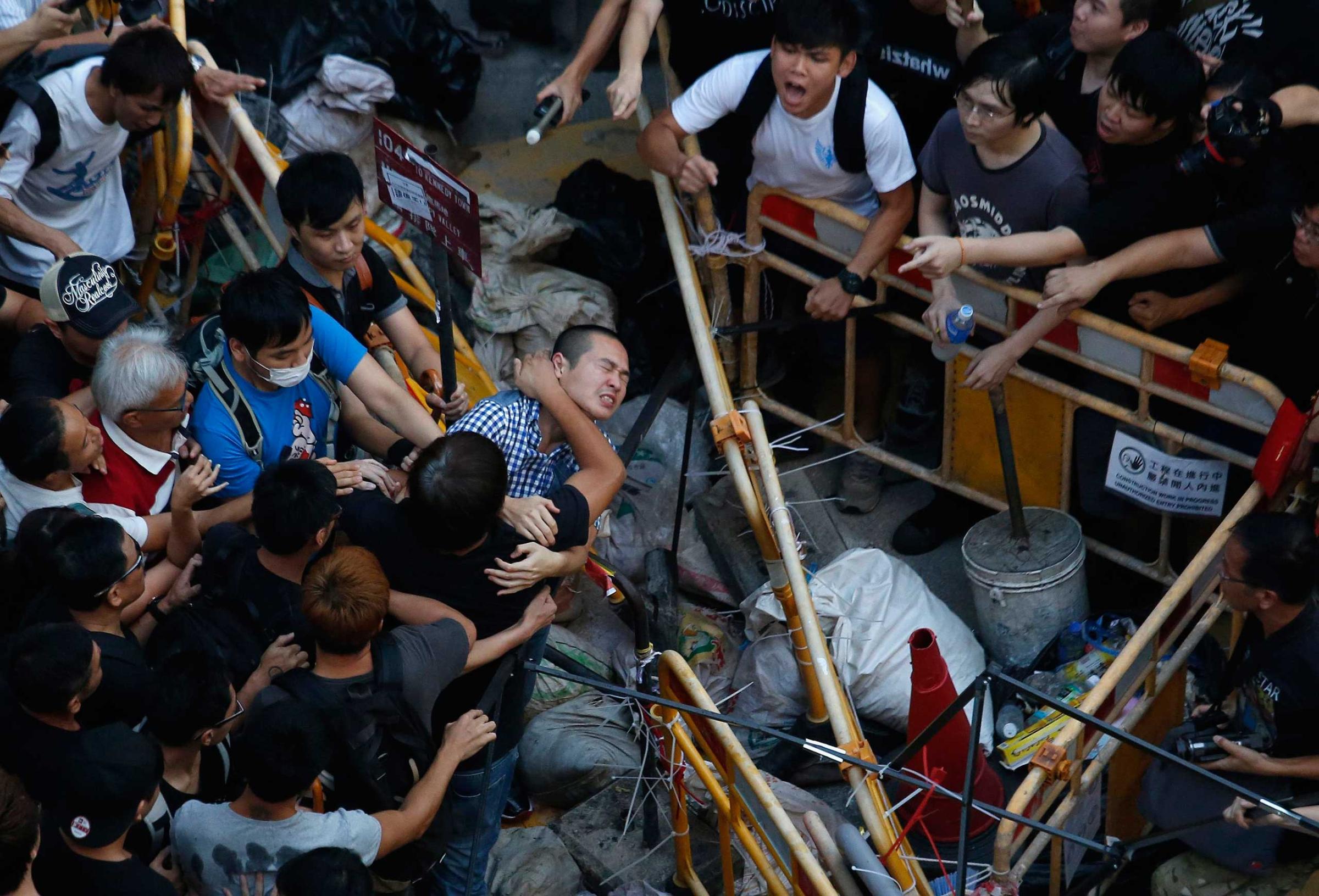 People try to prevent a man from removing a barricade set up by pro-democracy protesters blocking a main road at Hong Kong's shopping Mongkok district Oct. 4, 2014.
