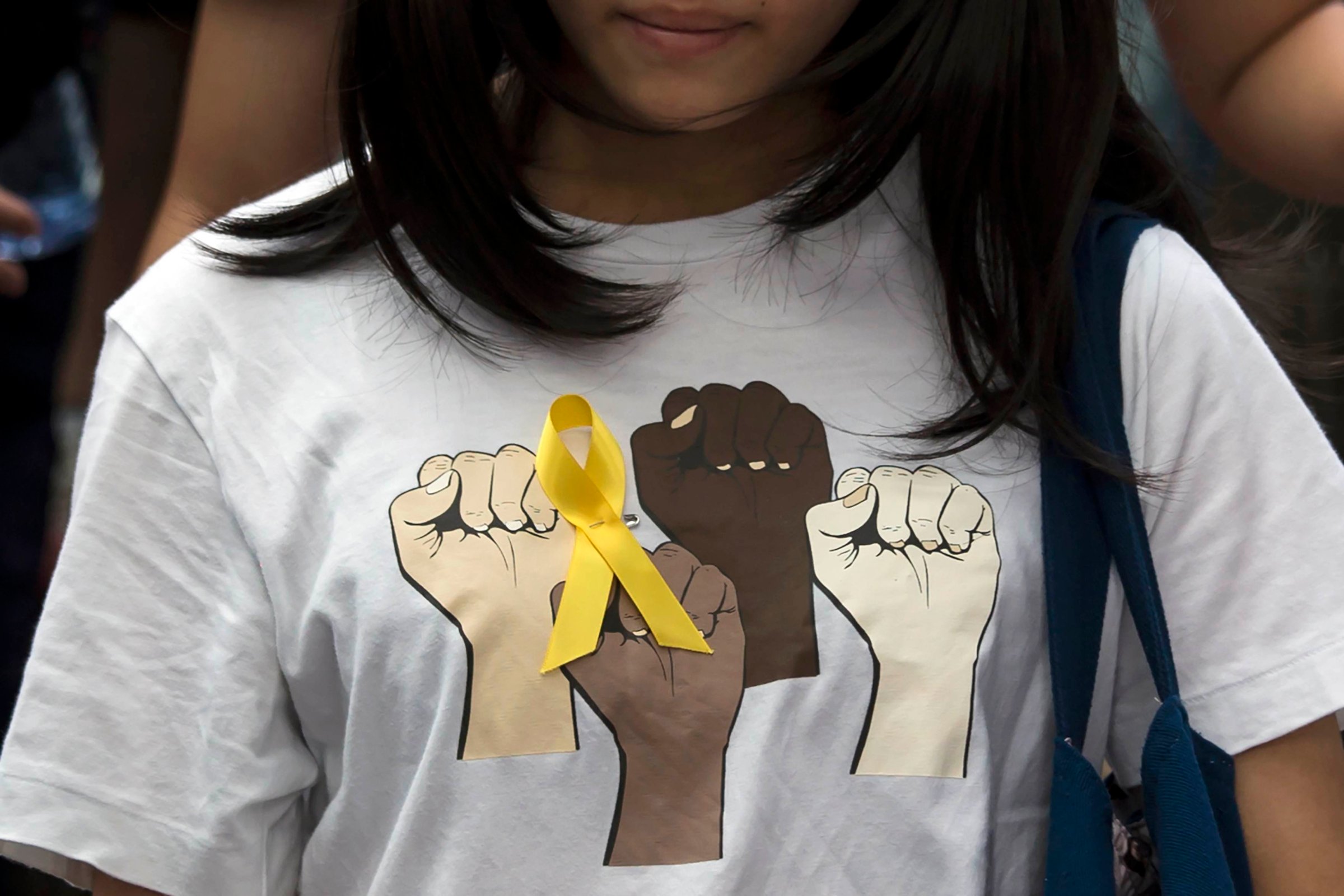 Secondary school student wears a yellow ribbon pinned to her T-shirt during a rally against Beijing's election framework for Hong Kong, outside the government headquarters in Hong Kong