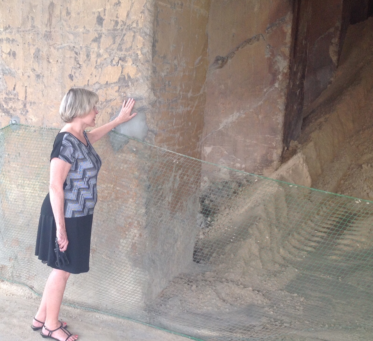 Kathy Holcomb touching the wall of one of the original buildings at the Ishihara Sangyo plant where her father labored as a POW in World War II (Kirk Spitzer)