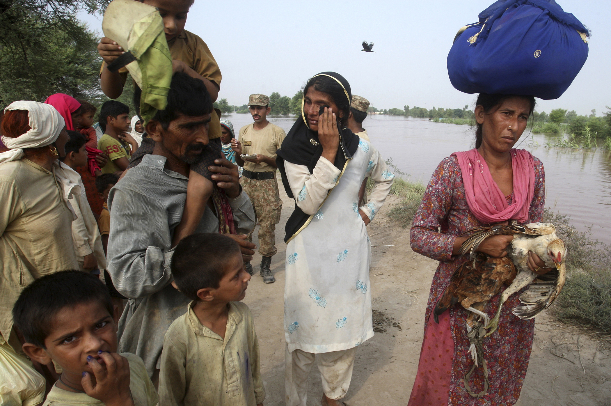 Pakistani villagers wait for boats to evacuate flooded areas along the Chenab River, in Jhang, Pakistan,Sept. 10, 2014.