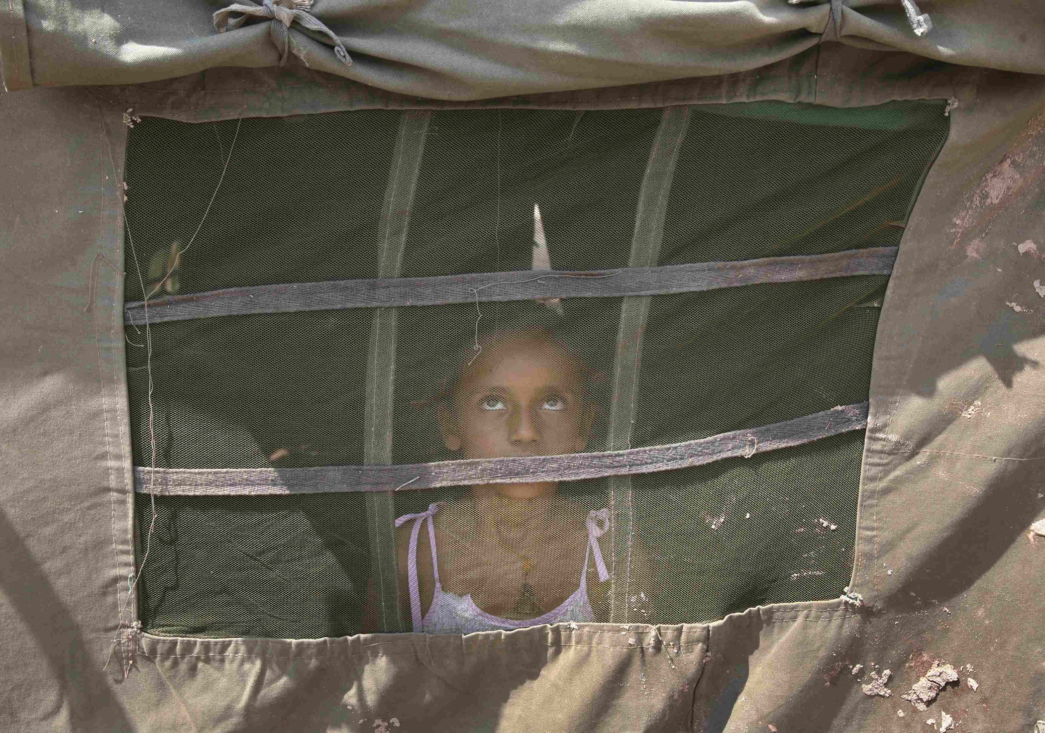 A girl from a flood-affected area watches a military chopper (not pictured) from inside an Indian Army tent at a relief camp on the outskirts of Jammu, Sept. 10, 2014.