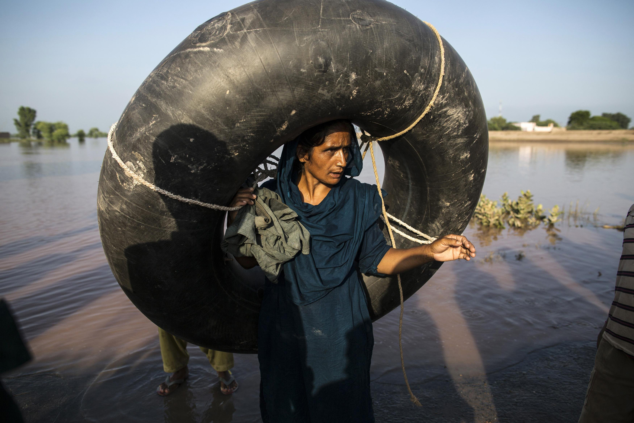 A Pakistani woman carries a rubber ring as she stands beside a flooded field following heavy rain in Cheniot, Punjab Province, Sept. 9, 2014.