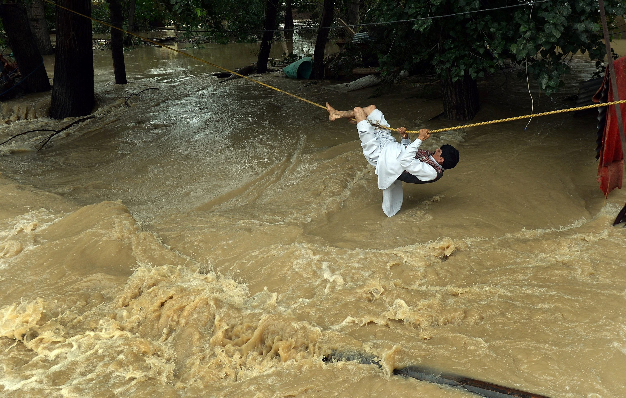 An Indian Kashmiri man crosses over flood waters with the use of a rope in Srinagar on Sept. 9, 2014.