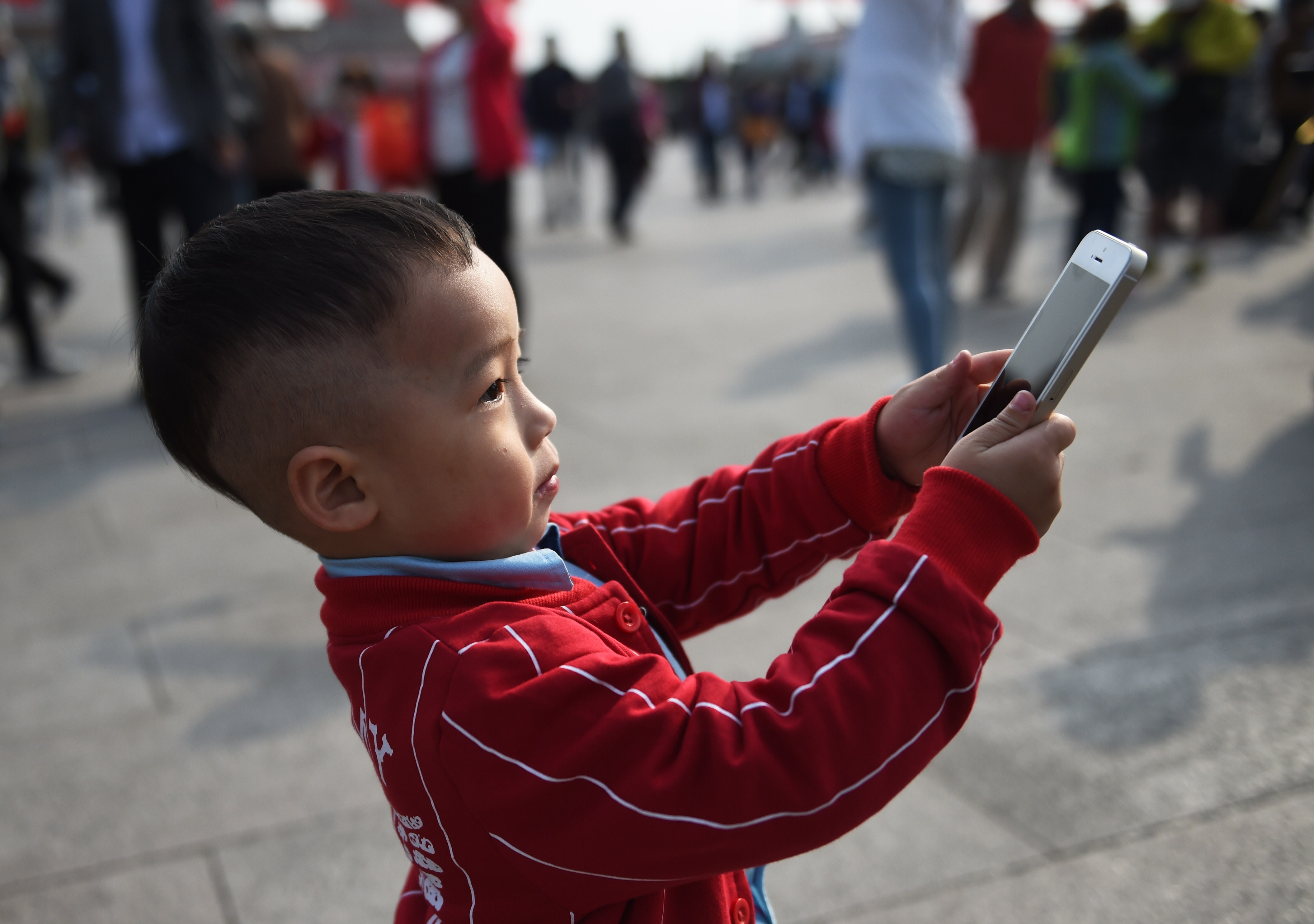 A young boy uses an iPhone to take photos in Tiananmen Square in Beijing on September 30, 2014. (Greg Baker&mdash;AFP/Getty Images)