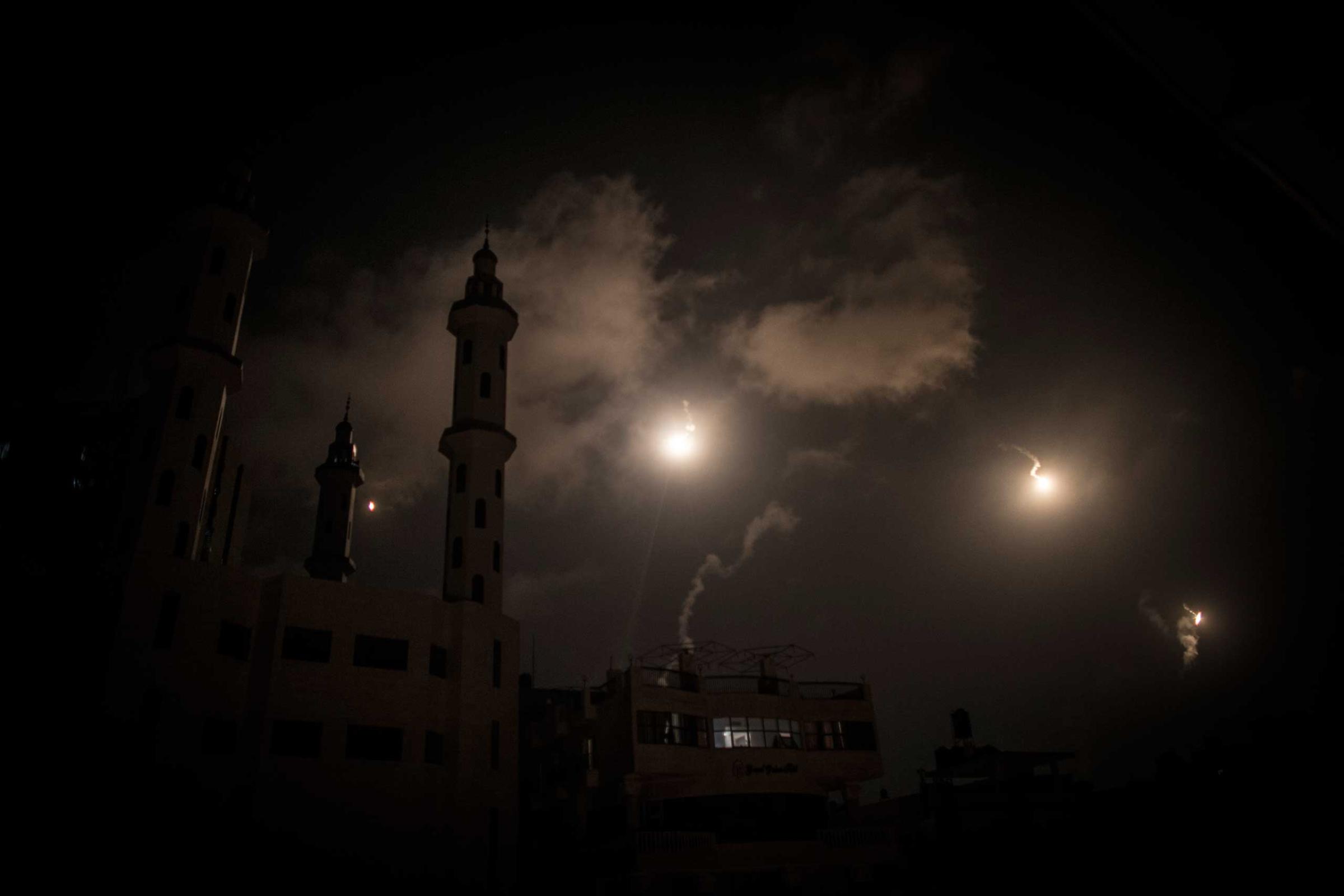 Illumination flares shot by Israeli Defense forces illuminate the minaret of a mosque in Gaza City
