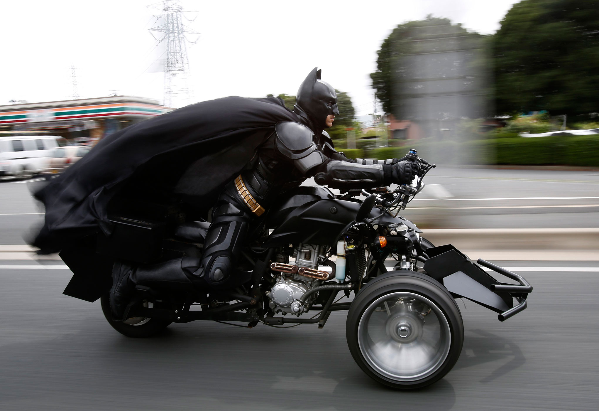 Chibatman rides his  Chibatpod,  a three-wheeled motorcycle.