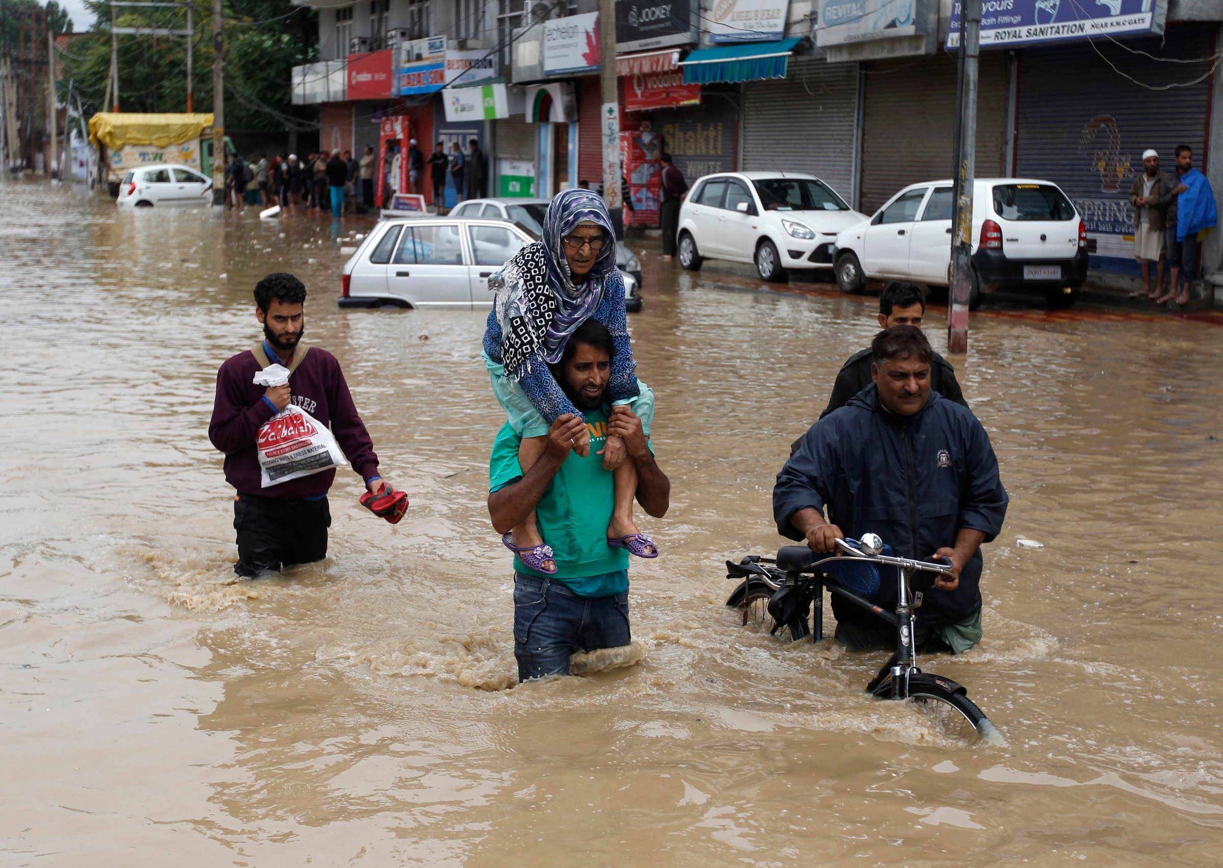 A Kashmiri man evacuates an elderly woman to a higher ground at a flooded road in Srinagar