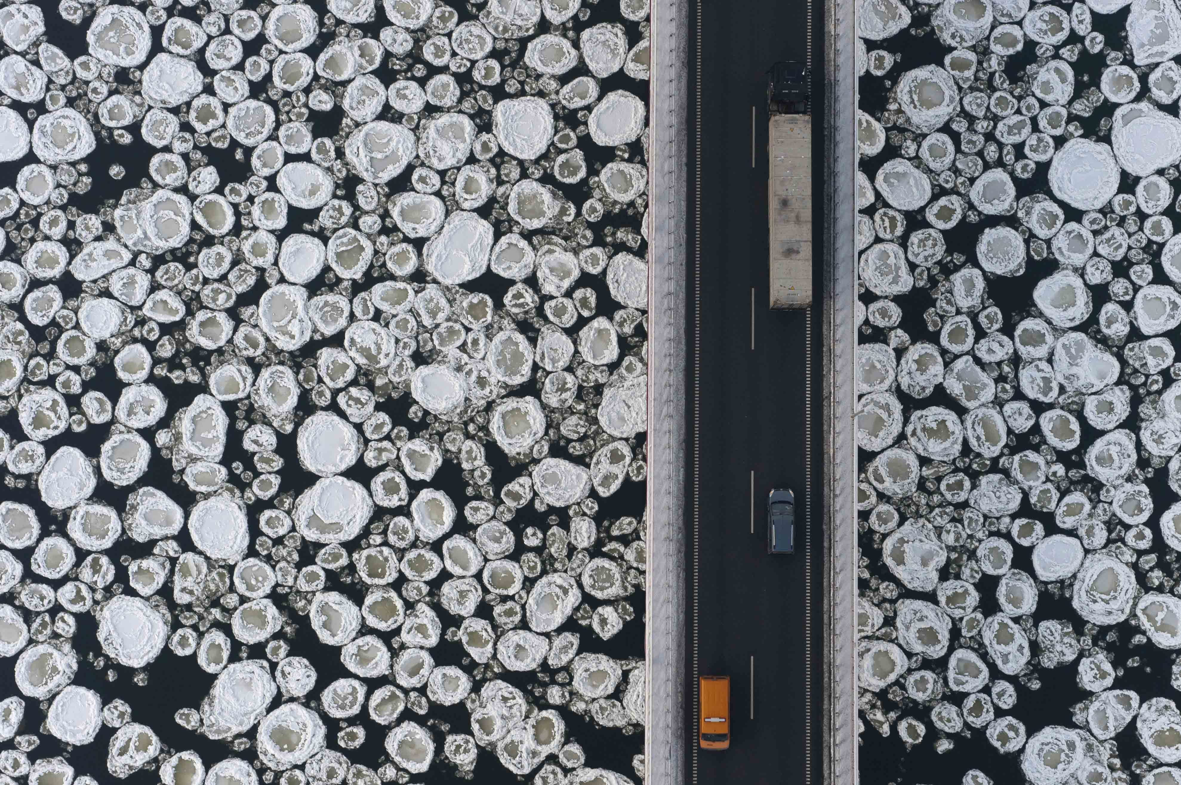 A lorry and cars travel on a road past the ice covered Vistula River near the village of Kiezmark, Poland.