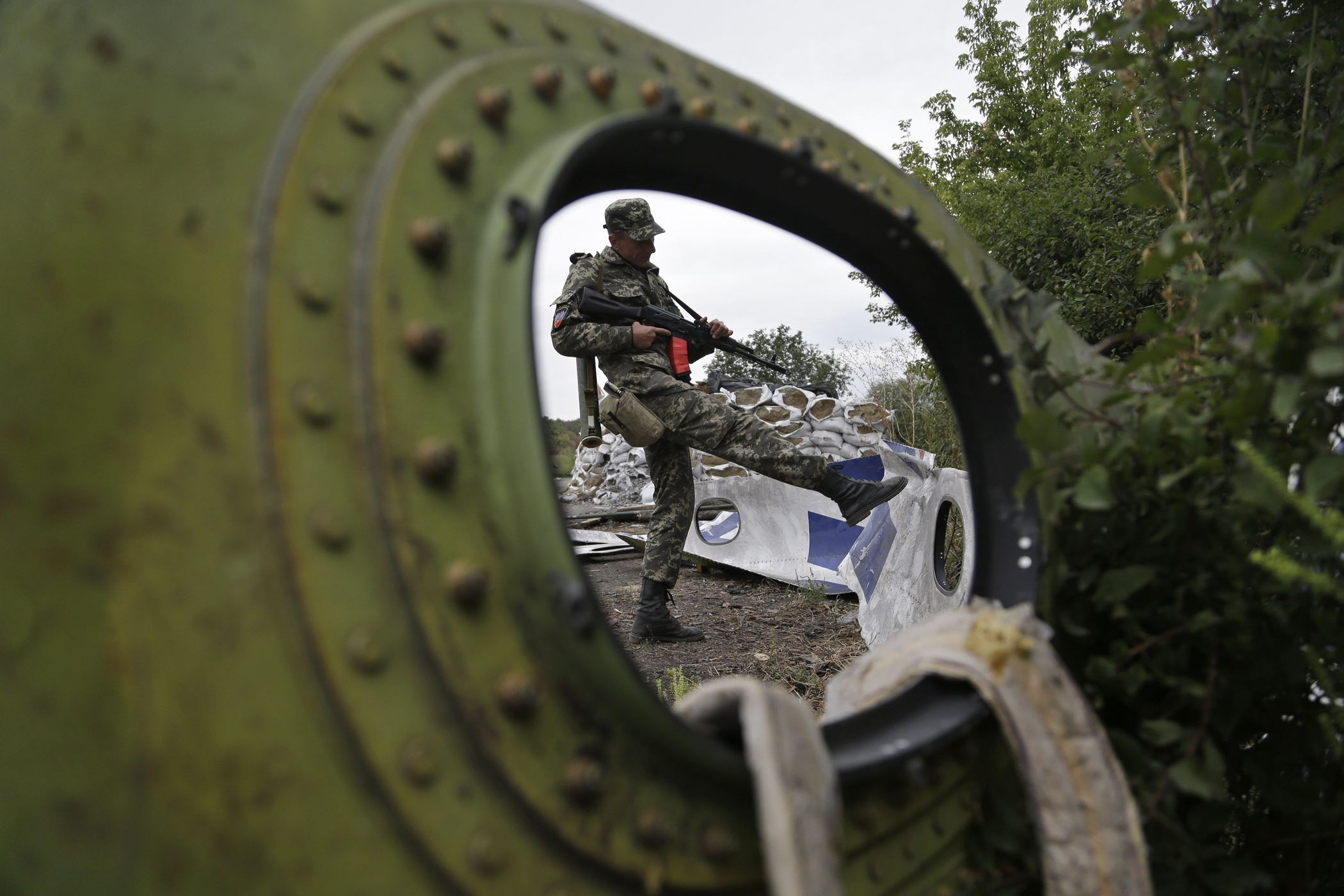 A Pro-Russian rebel looks at pieces of the Malaysia Airlines Flight 17 plane near village of Rozsypne, eastern Ukraine, Sept. 9, 2014.