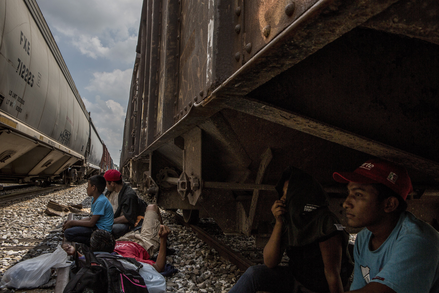 Eight-year-old Carlos Alberto Cruz Menjivar, left, who is traveling with his father, and others wait for the next train heading north, in Tierra Blanca, Mexico, Sept. 18, 2014.