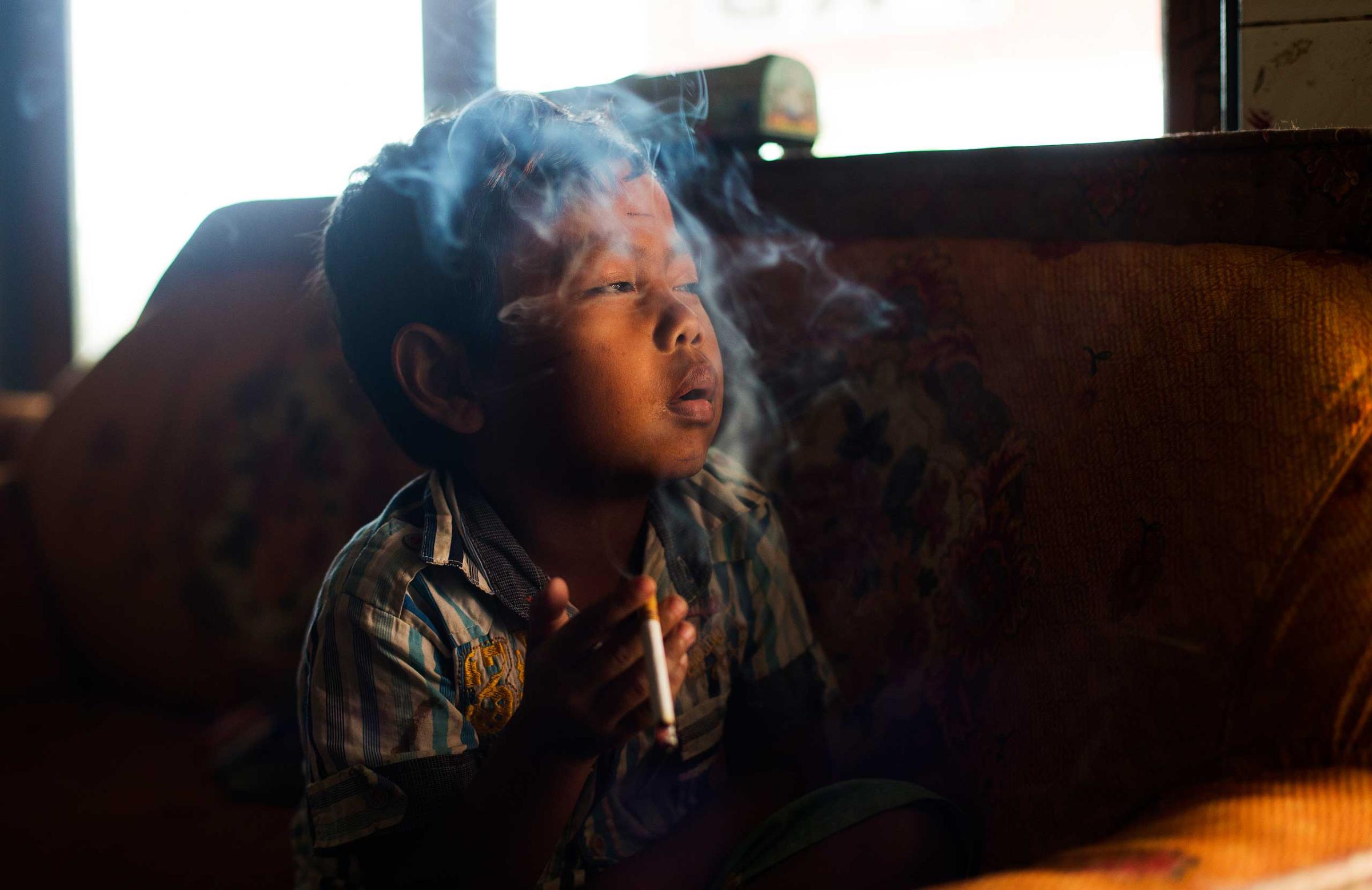 Dihan Muhamad smokes in his home in a village near the town of Garut, Indonesia on February 10, 2014.