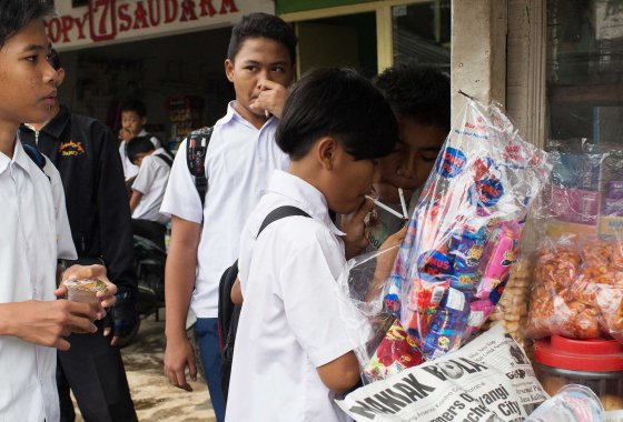 Groups of children buy single cigarettes and light them at a kiosk after school on February 12, 2014 in Jakarta, Indonesia. The children purchased cigarettes here without age identification and kiosks such as this one can be found near schools around the city.