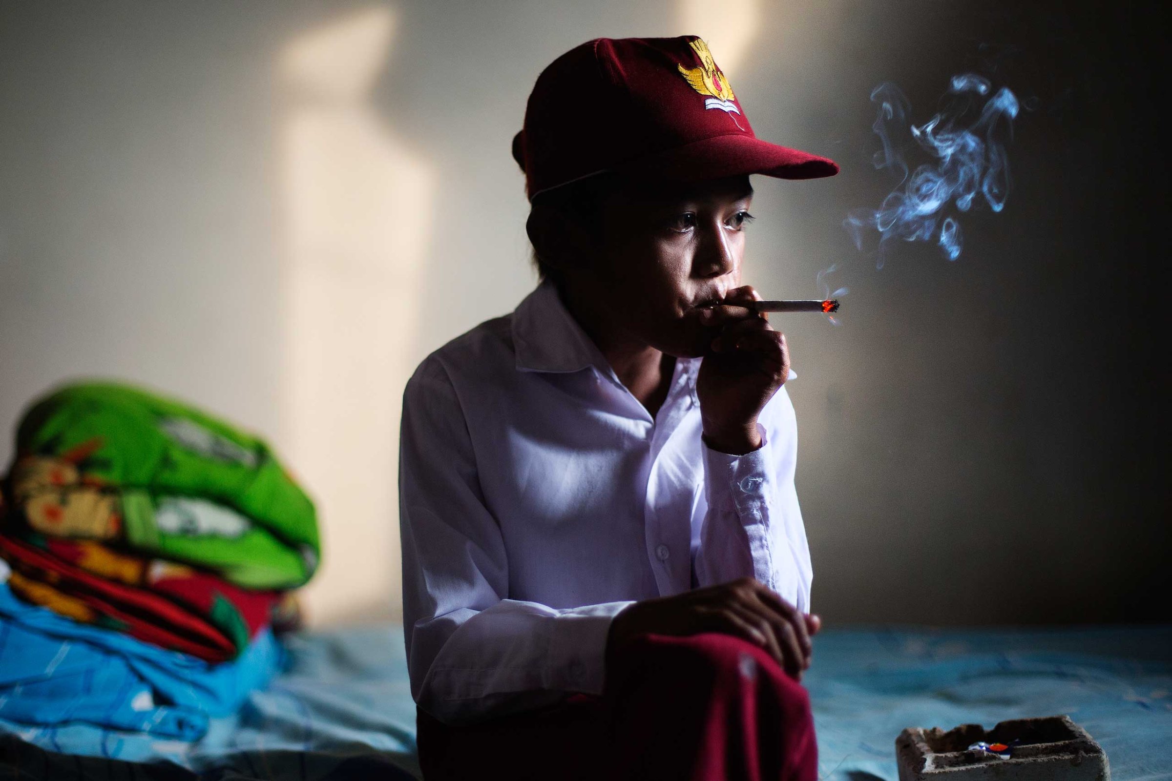 Ilham Hadi, who has smoked up to two packs a day and began when he was four years old, poses for a photo wearing his third grade uniform while smoking in his bedroom in a village near the town of Sukabumi, Indonesia on February 14, 2014.