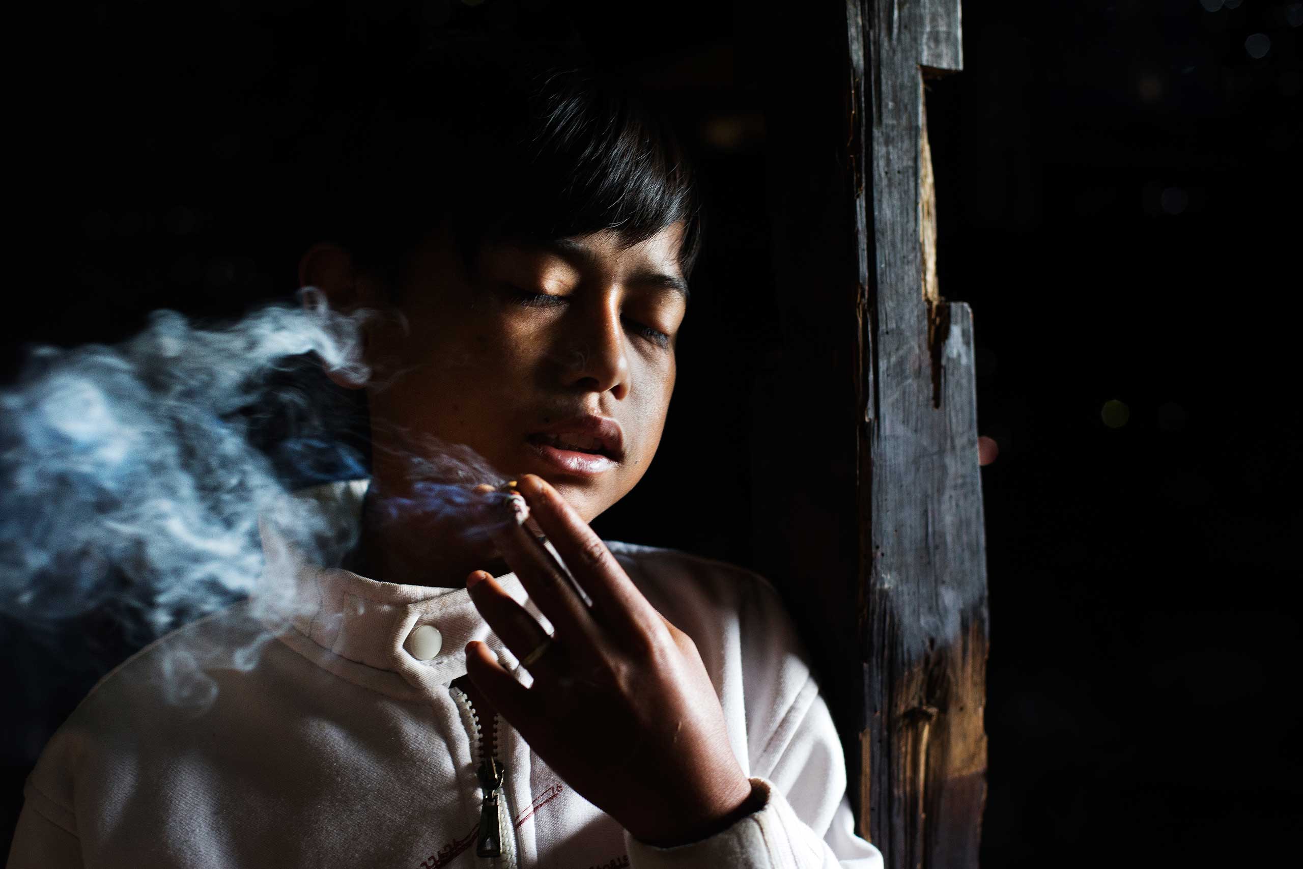 Illham Muhamad, who has smoked since he was five years old, poses for a photo as he slowly inhales his first cigarette of the day at his grandmother's home in Indonesia on February 10, 2014. He does not attend school and if his grandmother refuses to give him money to buy cigarettes he will cry and throw fits.
