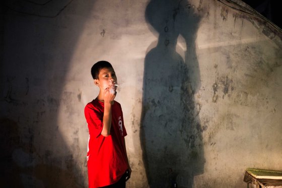 Andika Prasetyo, who smokes about a pack a day, has a cigarette outside an internet cafe where children are smoking inside in Depok, West Java, Indonesia on February 15, 2014.