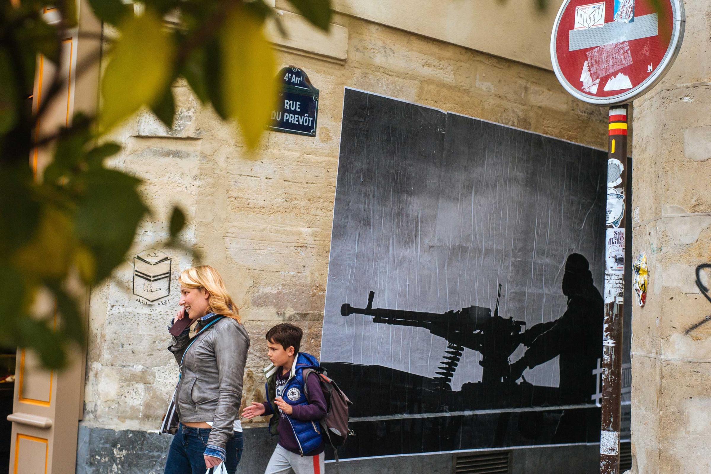 A woman and a child walk in front of one of Thibaut Camus' photographs on Rue du Prevot, Paris.