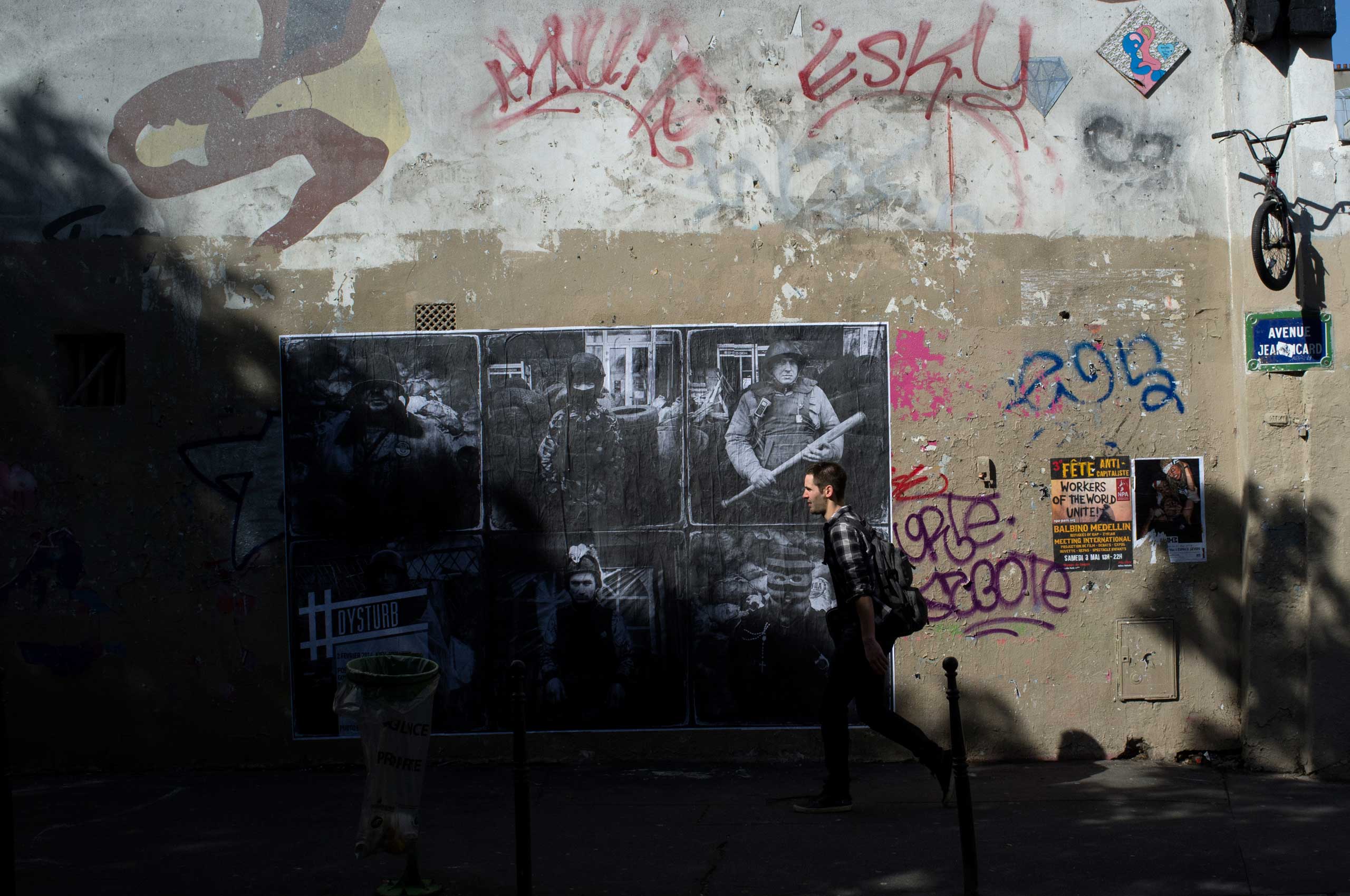 A man walks in front of Benjamin Girette's portraits shot in Ukraine in Feb. 2014