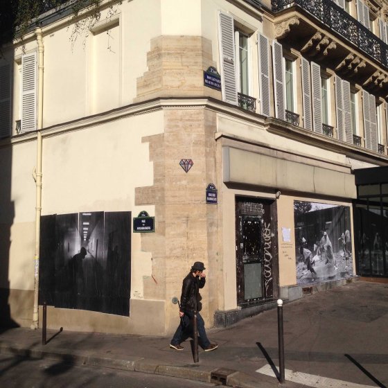 A man walks between two of Pierre Terdjman's photographs in Paris.