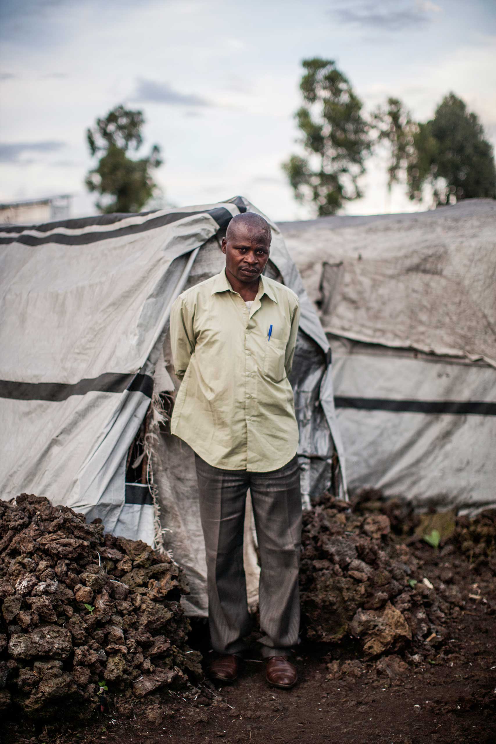 A displaced Congolese man stands for a portrait in front of the tent where he lives in the Mugunga camp, outside Goma.