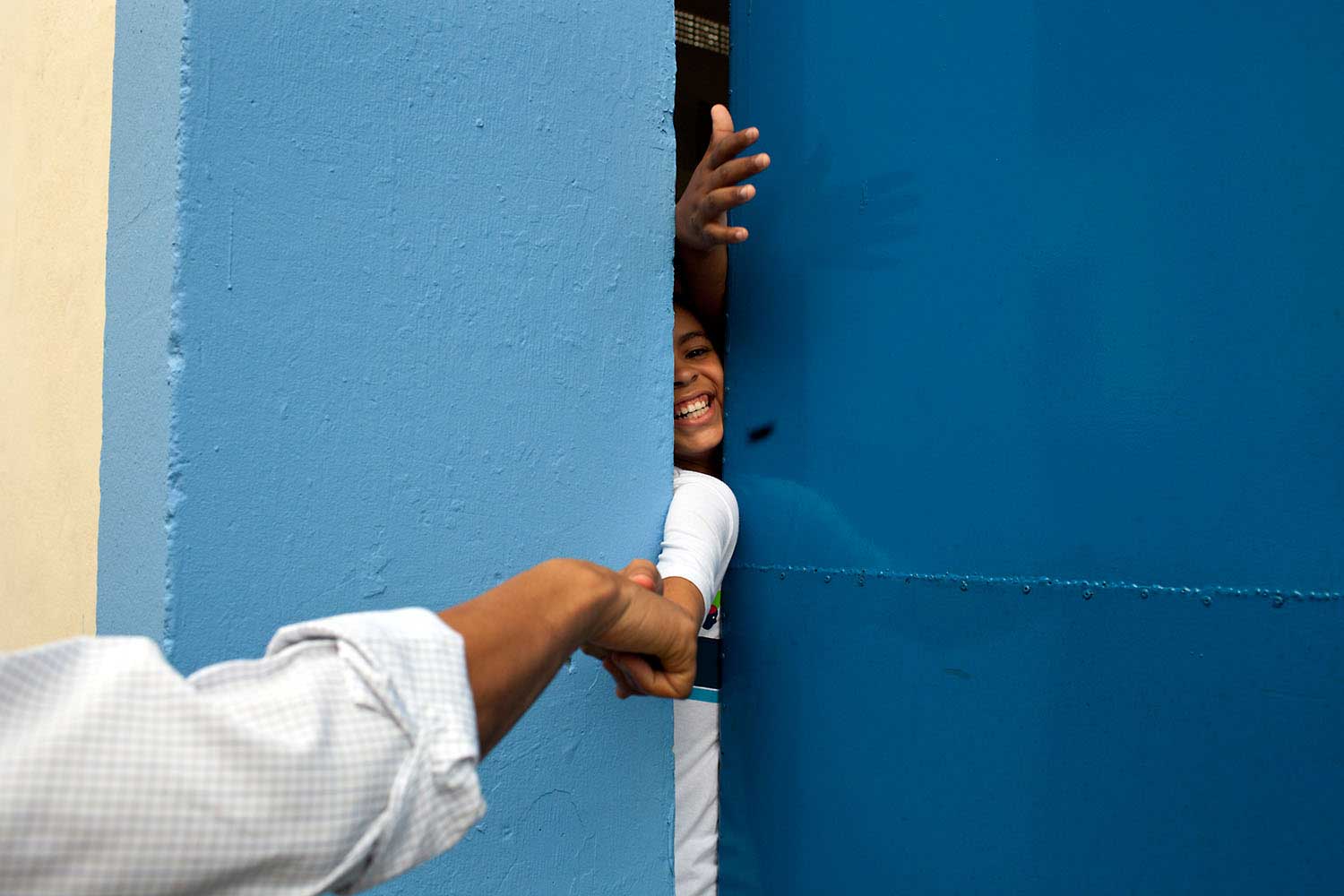 President Obama fist bumps a young person reaching through the door at the Cidade de Deus (City of God) favela Community Center in Rio de Janeiro, Brazil, March 20, 2011.