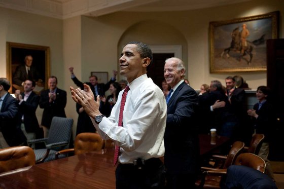 The President, Vice President and senior staff applaud after watching on television the House vote on H.R. 4872 for health care reform, in the Roosevelt Room of the White House, March 21, 2010.