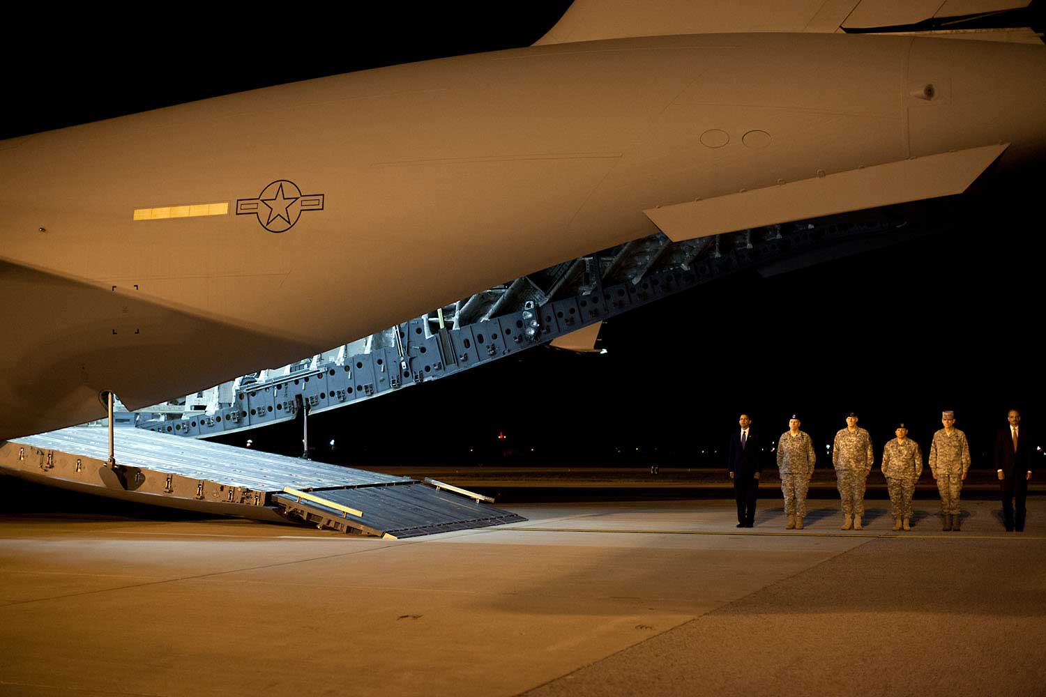 “This photo was taken about 4AM, Oct. 29, 2009, after the President made an unannounced trip to Dover Air Force Base to pay respects to fallen troops coming back from Afghanistan. After meeting privately with the families, the President walked alone up the ramp of the cargo plane carrying the 18 caskets, all draped in American flags. I could see the emotion on his face as he walked from casket to casket, leaving a Presidential coin on each. When he was done, he paused for a few minutes, head bowed in prayer. I heard him tell others later how that was the most difficult moment of his Presidency thus far. Out of respect for the families, not all of who wanted their ceremony photographed, we can’t show those pictures (but they will become part of Presidential archive.)"