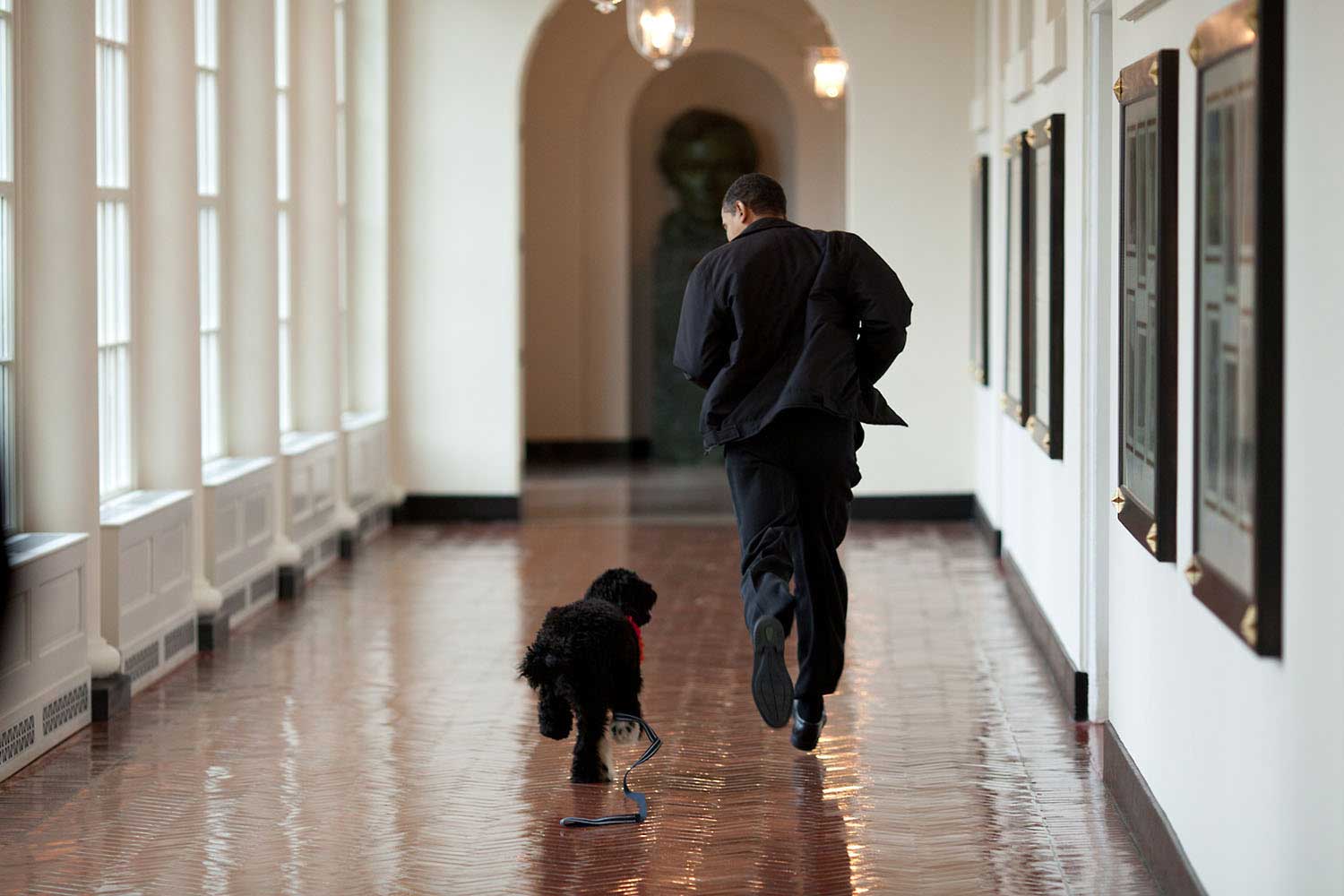 “The Obama family was introduced to a prospective family dog at a secret greet on March 15, 2009. After spending about an hour with the dog, the family decided he was the one. Here, the dog ran alongside the President in an East Wing hallway. The dog returned to his trainer, while the Obamas embarked on their first international trip. I had to keep these photos secret until a few weeks later, when the dog was brought ‘home’ to the White House and introduced to the world as Bo.”