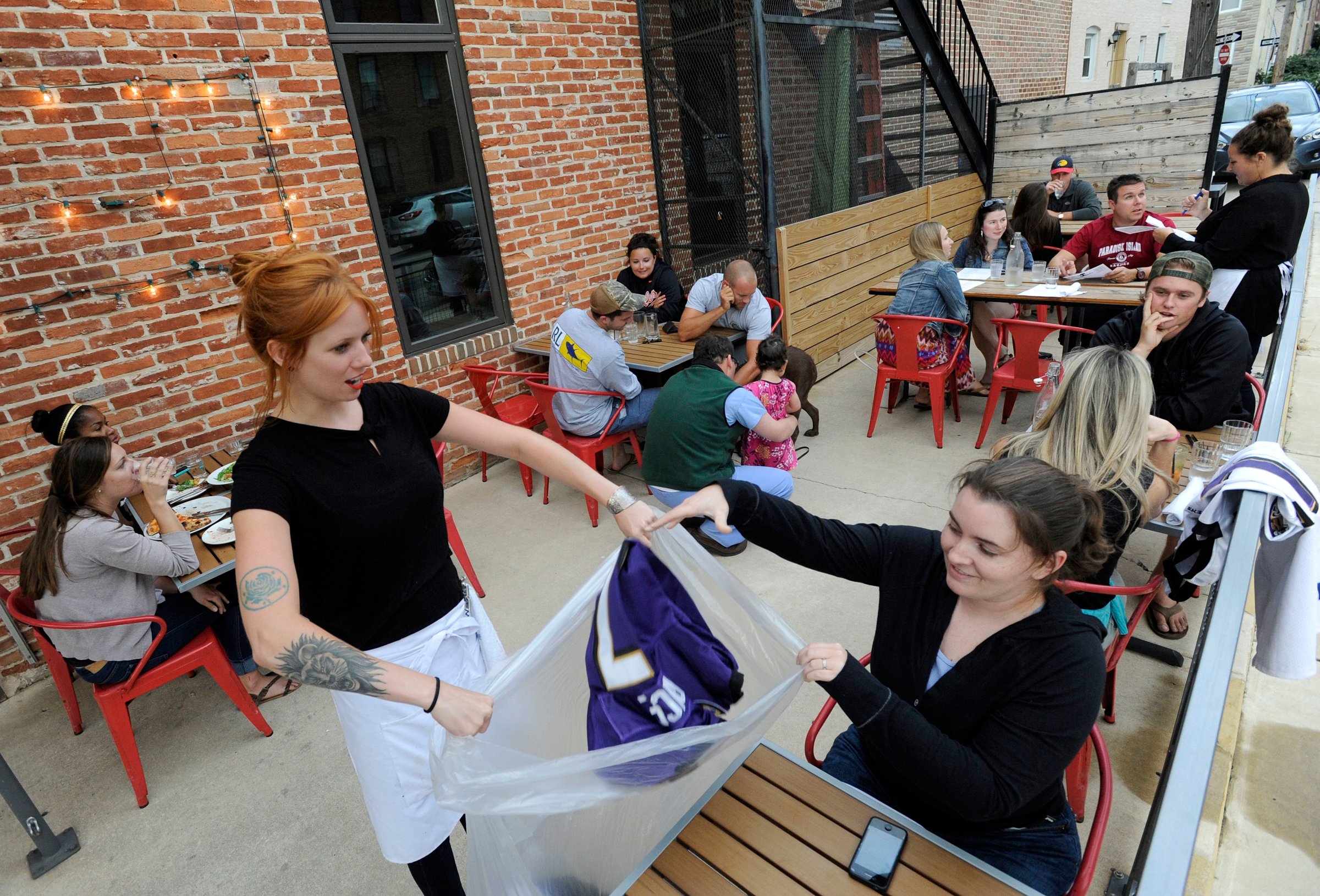 Bartender Abby Hopper, left, of Baltimore, collects a Ray Rice Baltimore Ravens football jersey from Erin McGonigle, right, of Arbutus, Md., at Hersh's Pizza and Drinks, a Baltimore restaurant that offered a free personal pizza in exchange for Rice jerseys on Sept. 8, 2014.